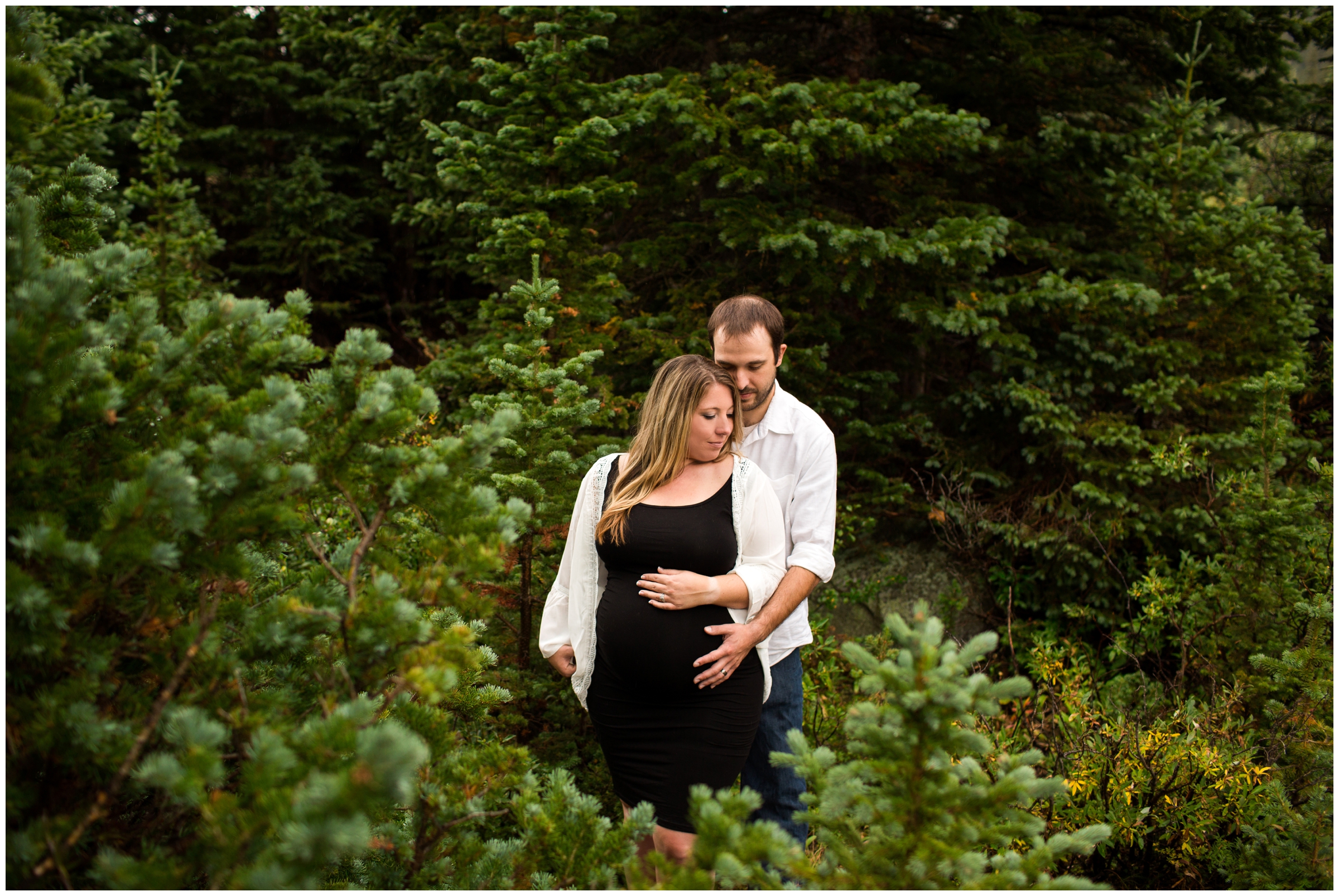 couple embracing against pine tree backdrop by Colorado maternity photographer Plum Pretty Photography 
