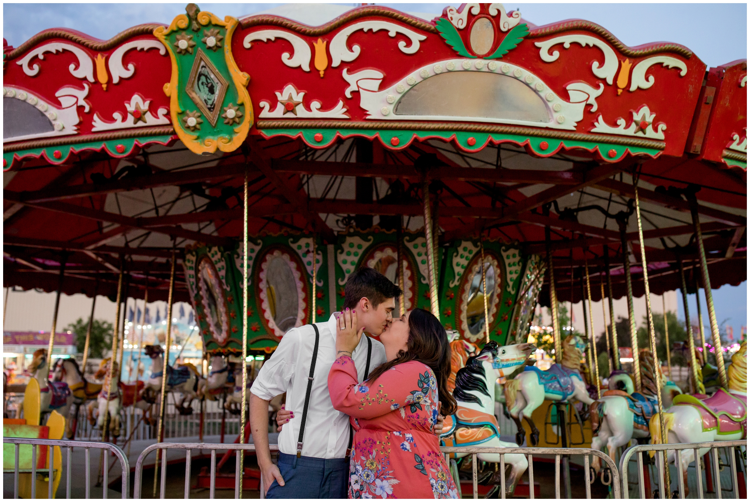 couple kissing in front of carousel during Longmont Colorado carnival engagement photography session 