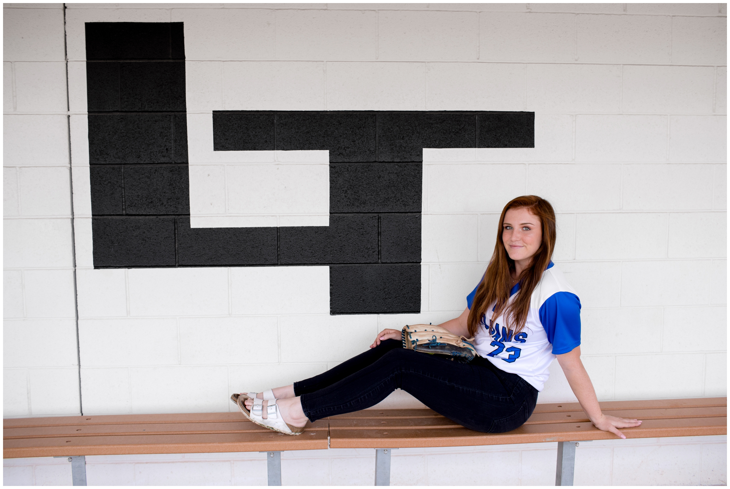 female softball player posing in dugout during Colorado sports senior photos 