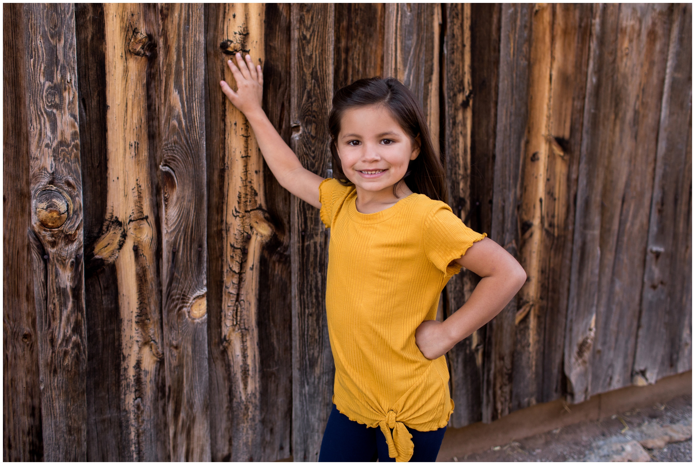 girl leaning against a barn during rustic Colorado family pictures 