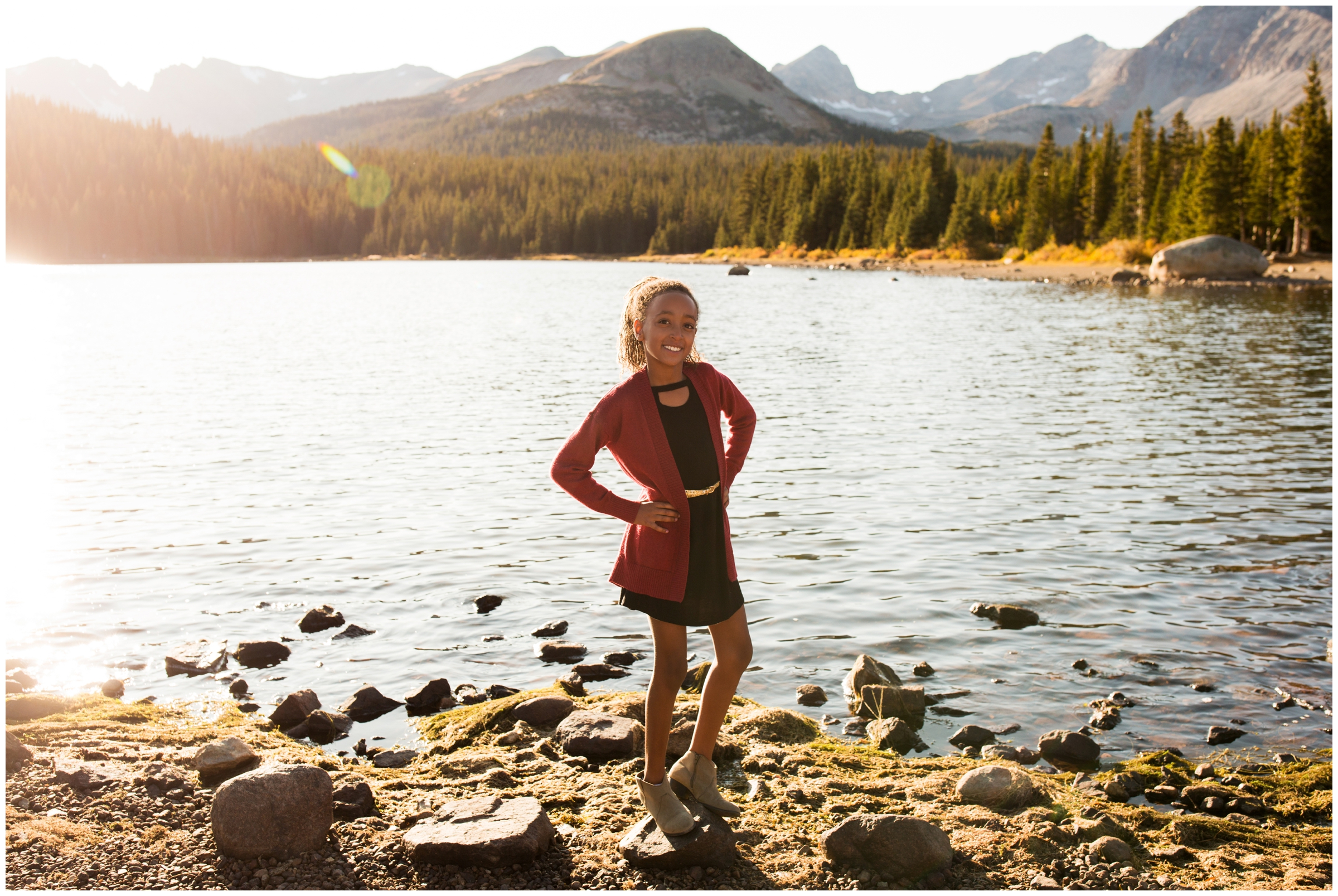 young girl posing in front of mountain lake during fall photography session 