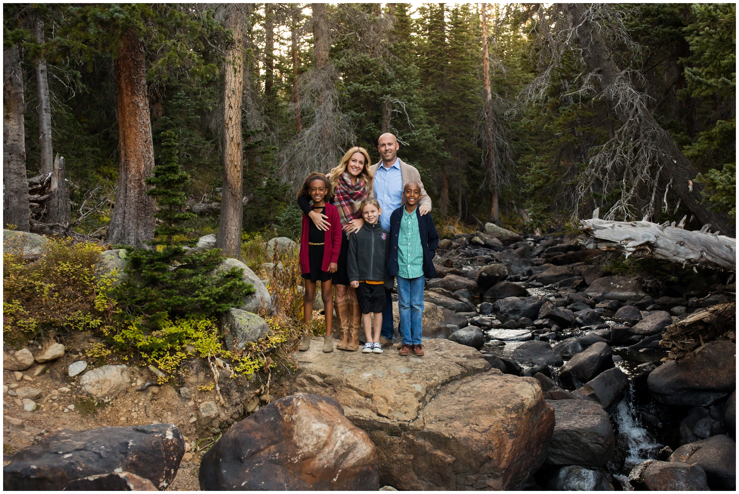 family posing by small waterfall during Colorado forest family portraits by Plum Pretty Photo 