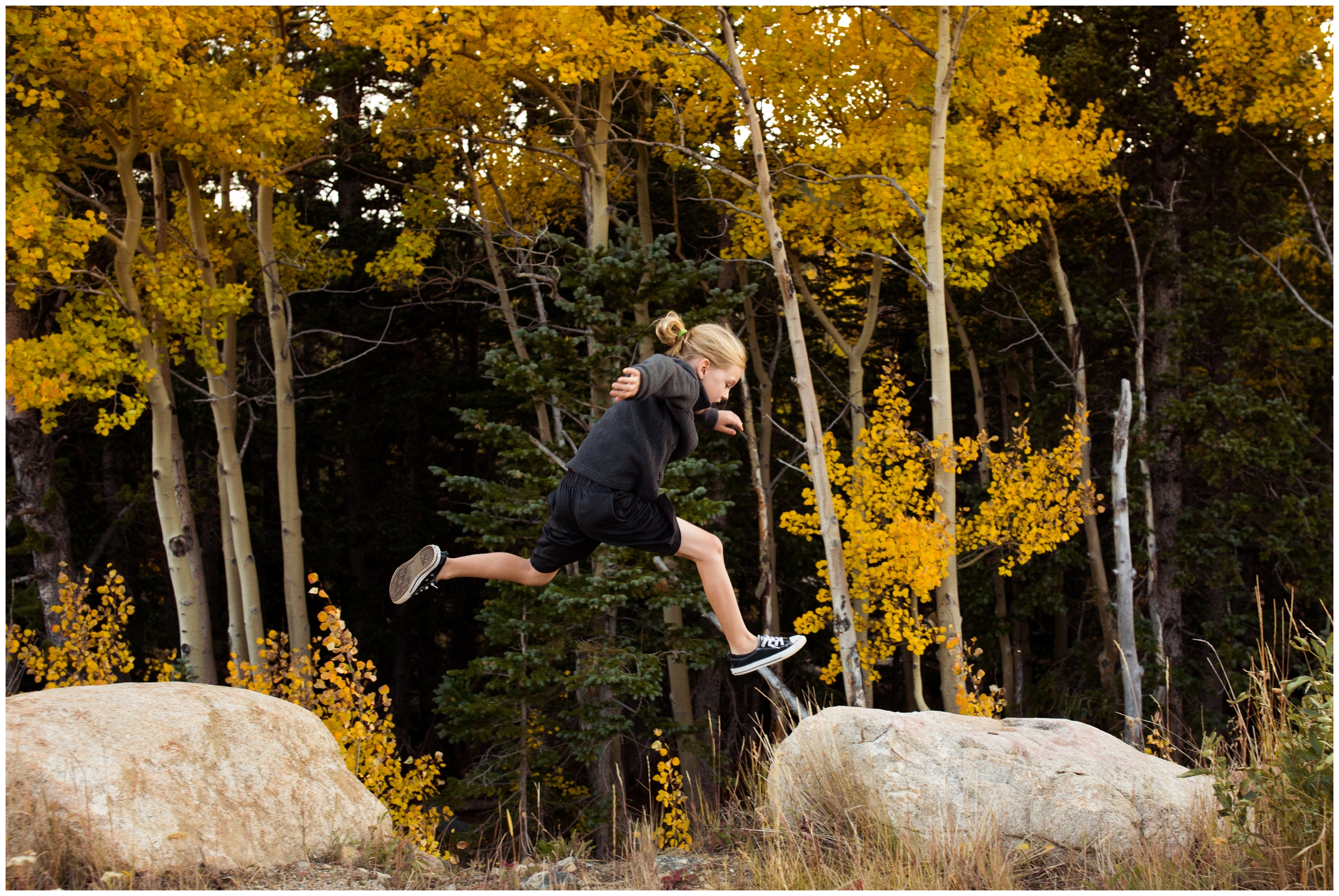 kid jumping on rocks during candid Colorado fall family pictures