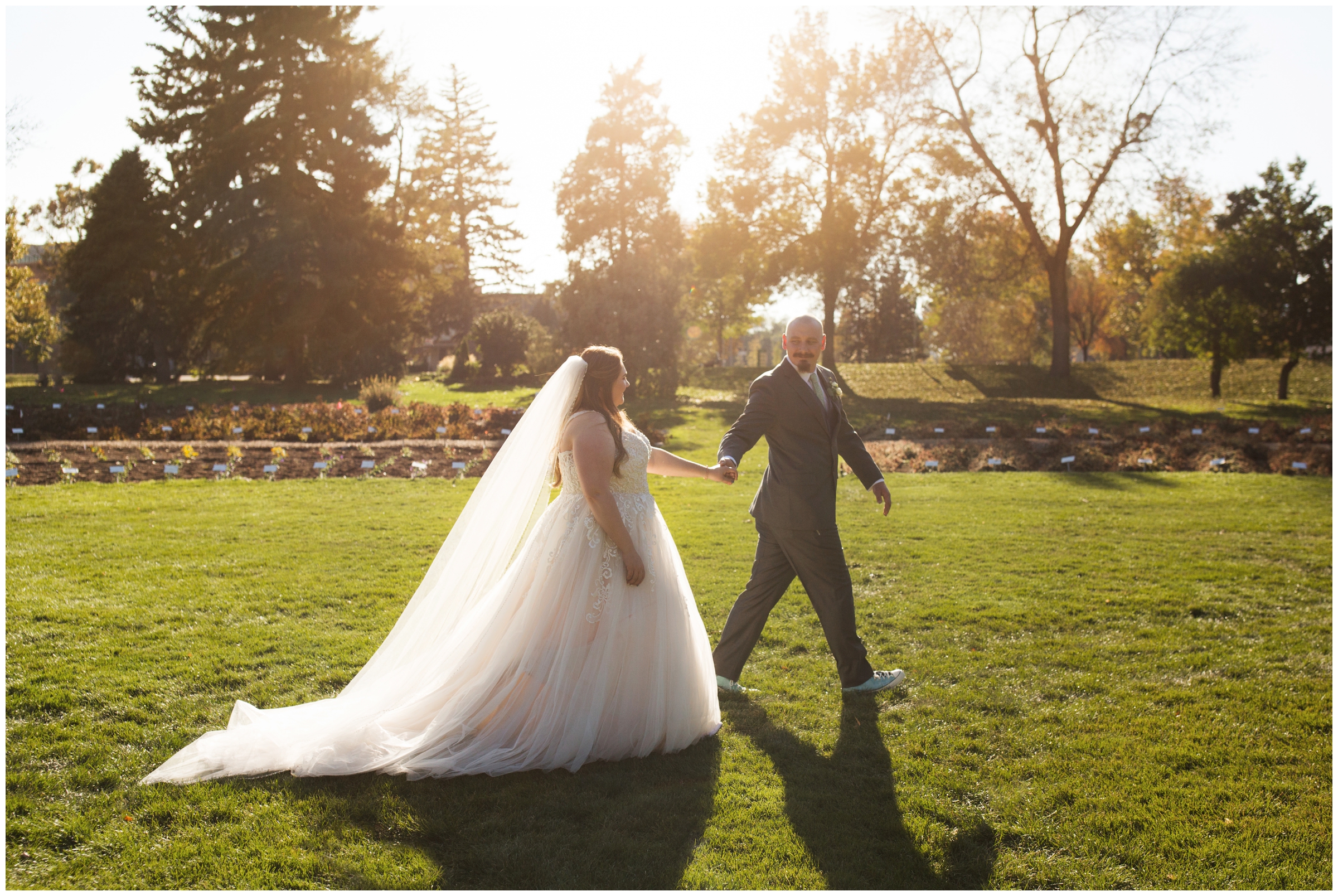 bride and groom walking through a field at Fort Collins Colorado State University wedding 