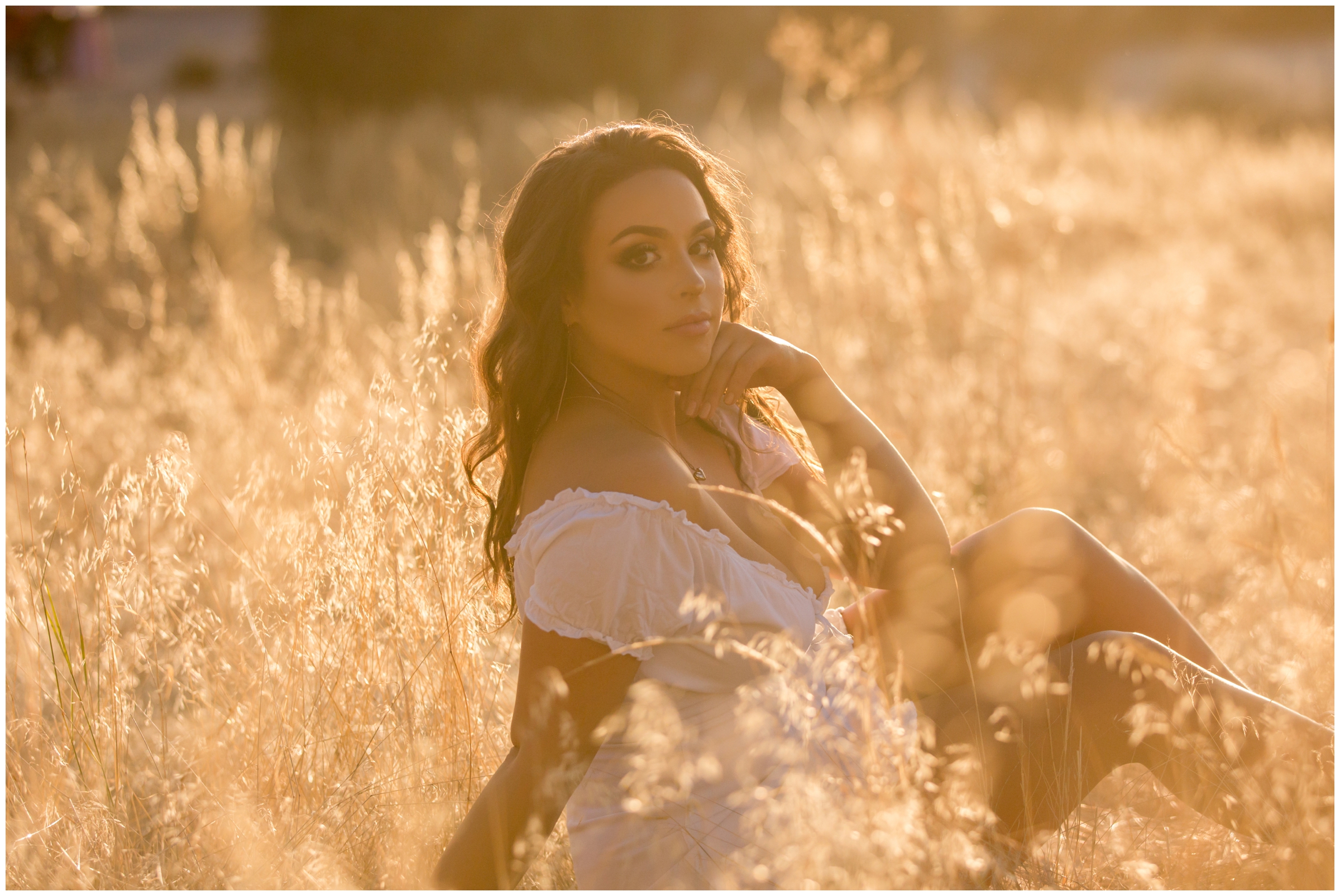 teen sitting in golden field during sunny Colorado senior photos 