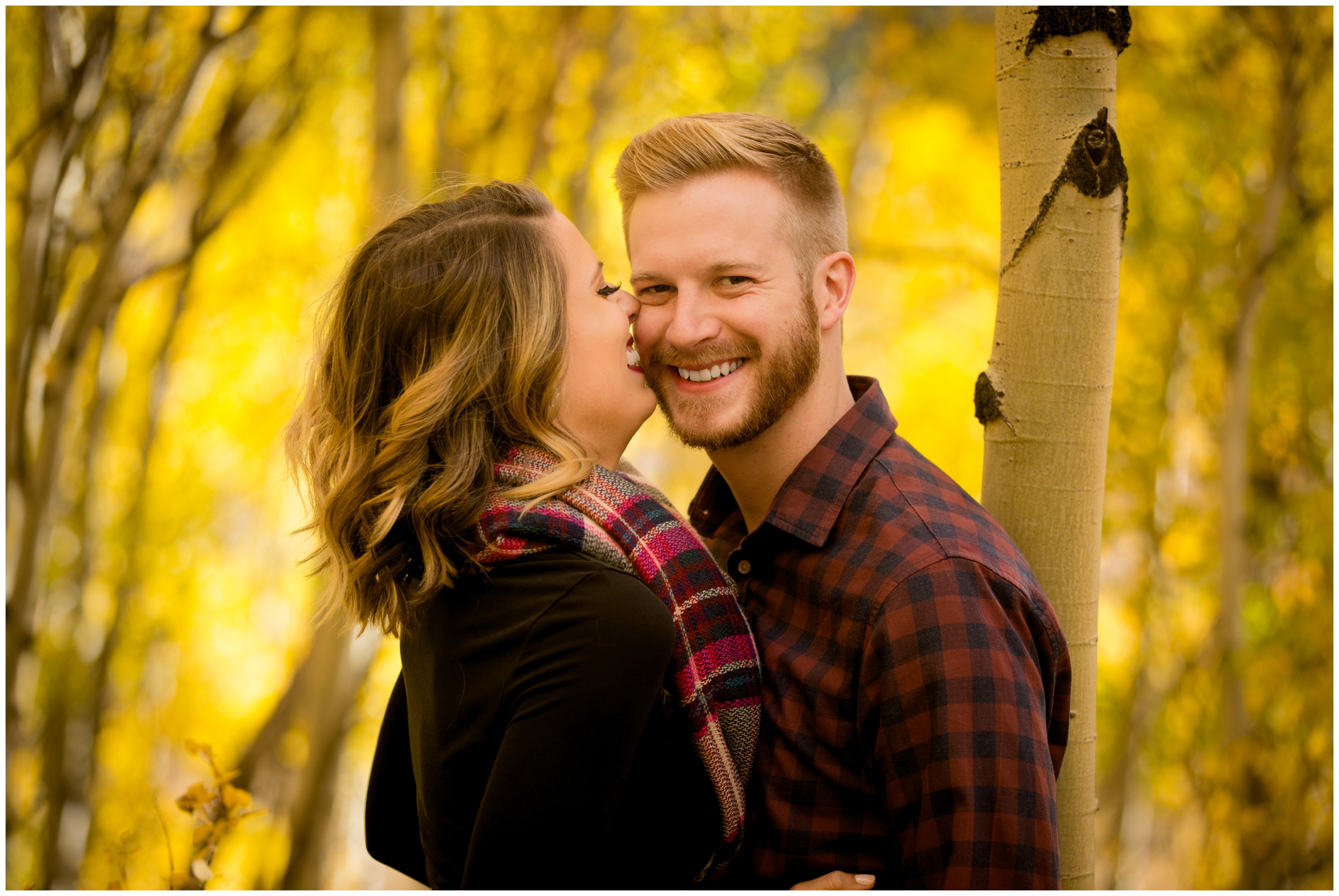 woman kissing fiancé's cheek during Colorado mountain engagement photos 