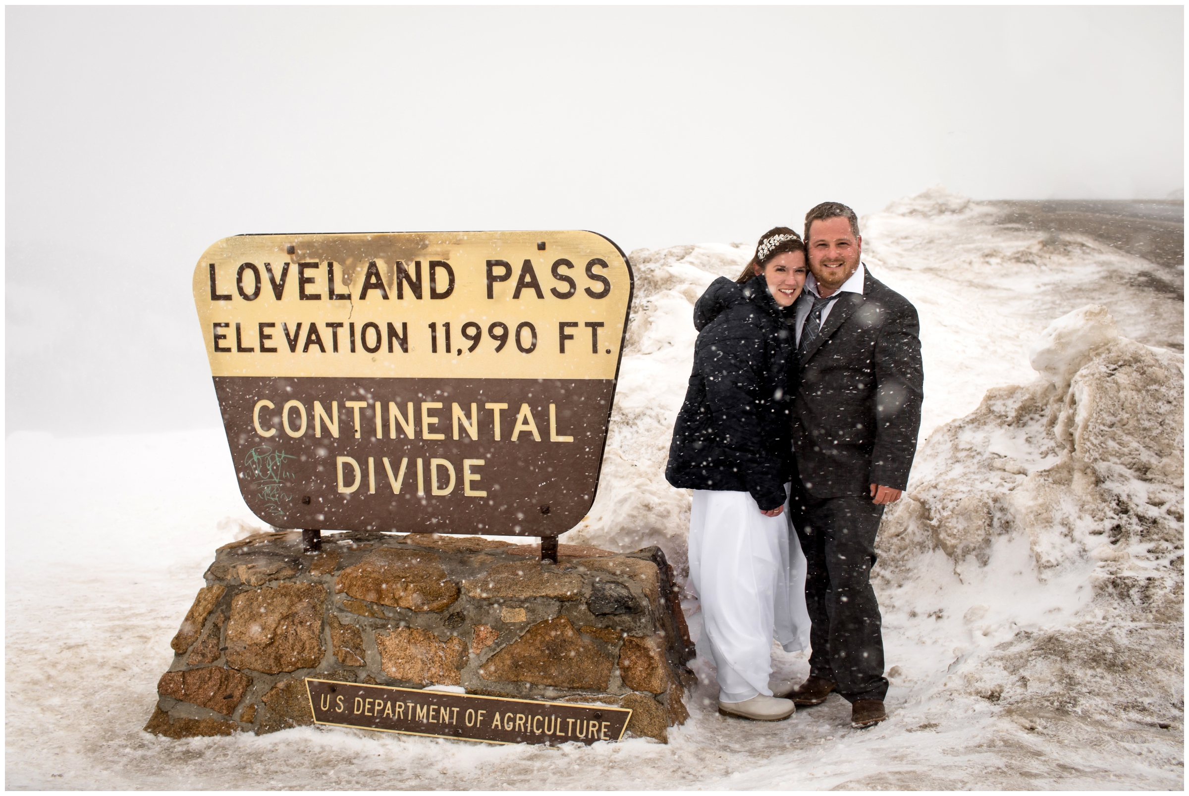 couple posing next to the Loveland Pass sign in Colorado mountains 