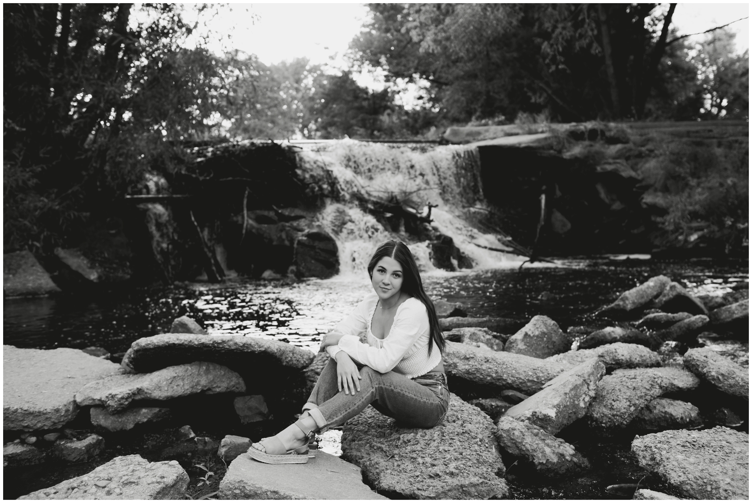 teen sitting in front of waterfall during Colorado summer senior photos 