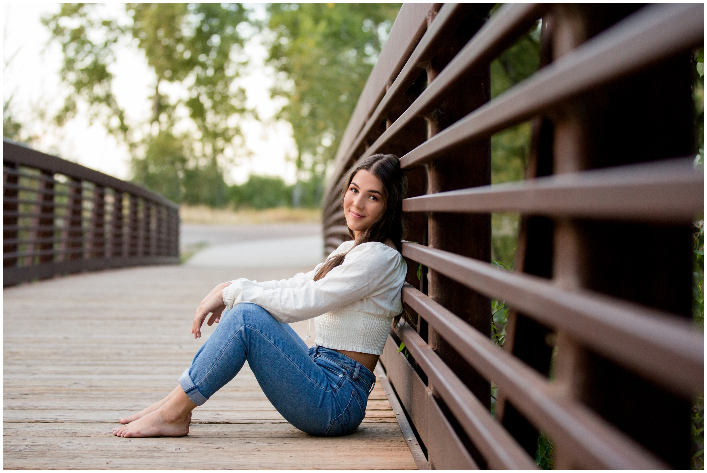 girl sitting on bridge at Golden Ponds Colorado during Erie High senior photography session