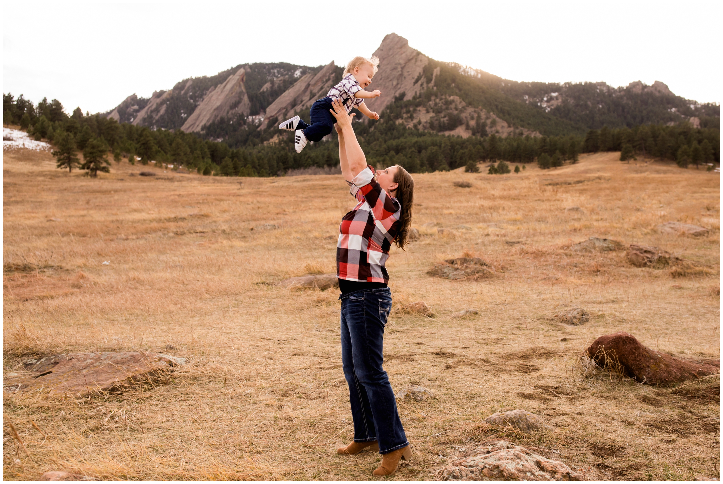 mom throwing son into the air during Colorado fall family portraits at Chautauqua Park Boulder 
