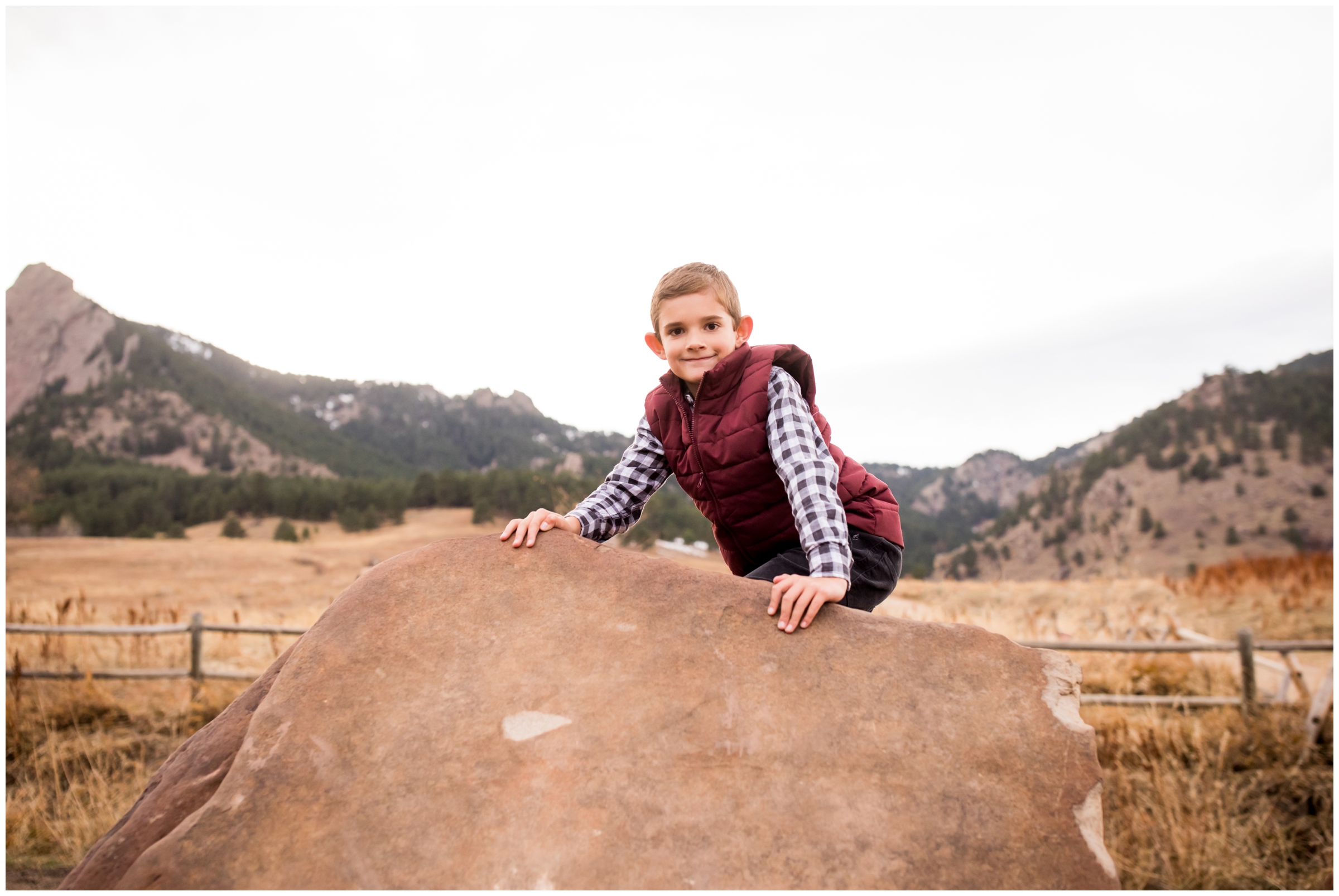 little boy climbing on rocks during Boulder Colorado fall portraits 