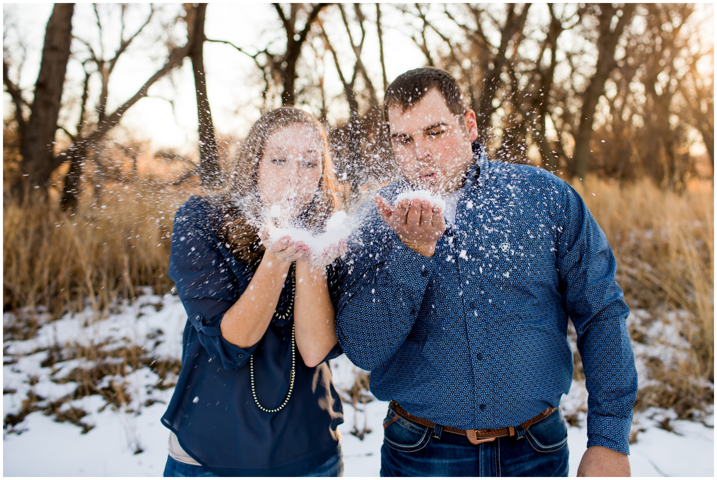 couple blowing snow during winter engagement pictures in Eastern Colorado 