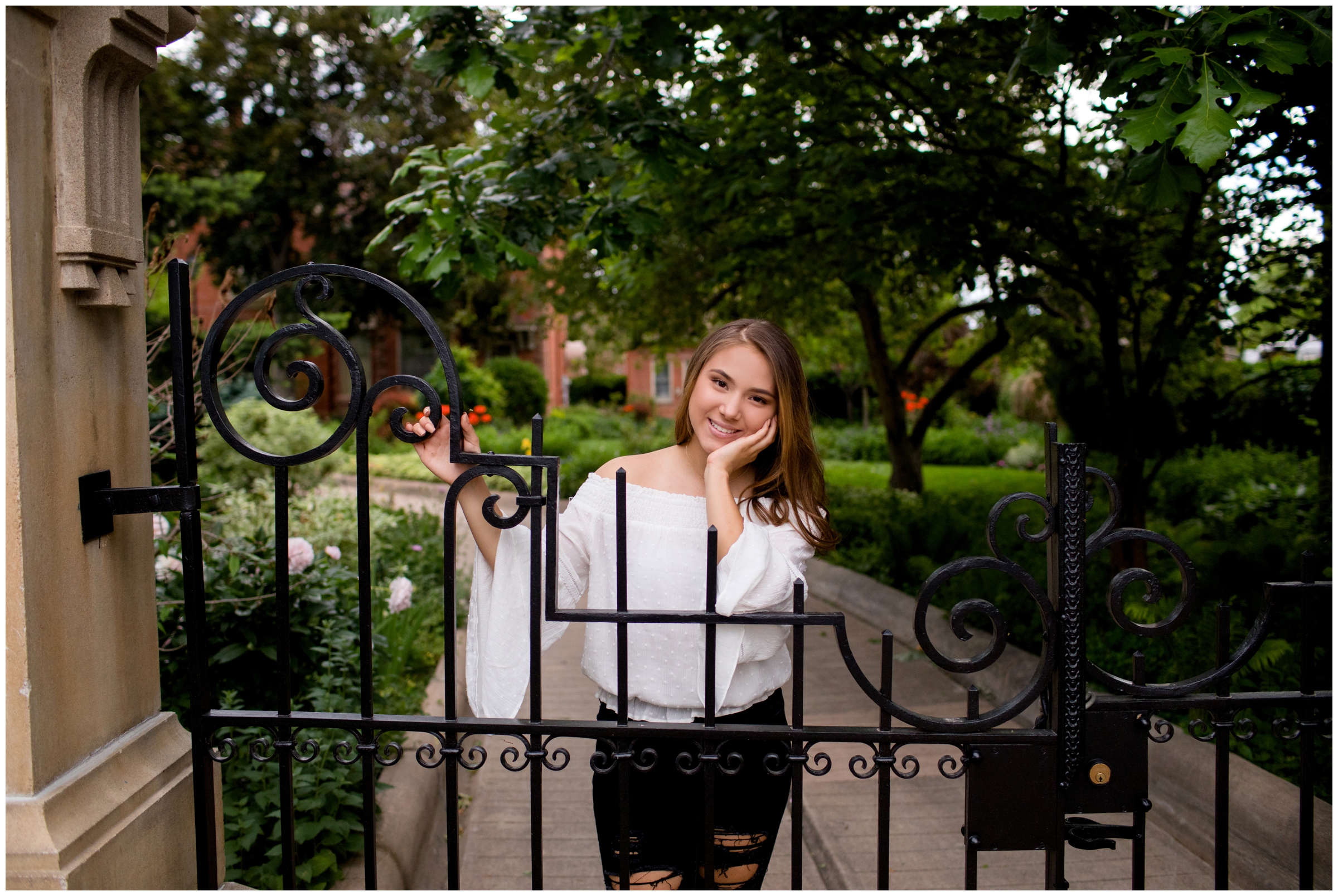 teen posing against wrought iron fence during Longmont senior photography session 
