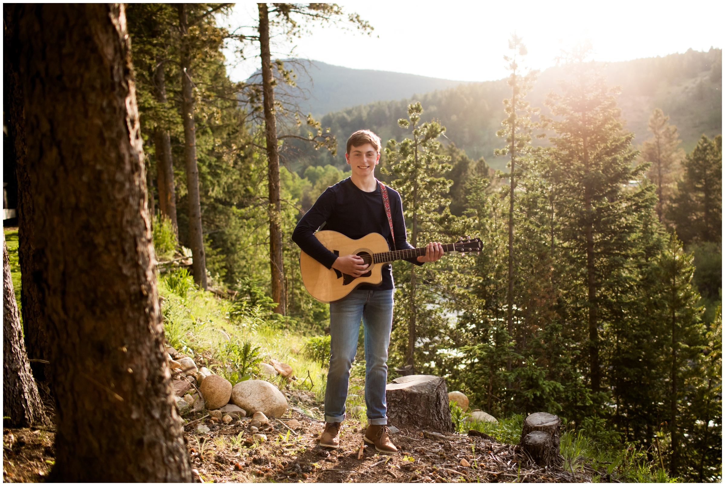 teen boy playing guitar with mountains in background during Colorado senior pictures 