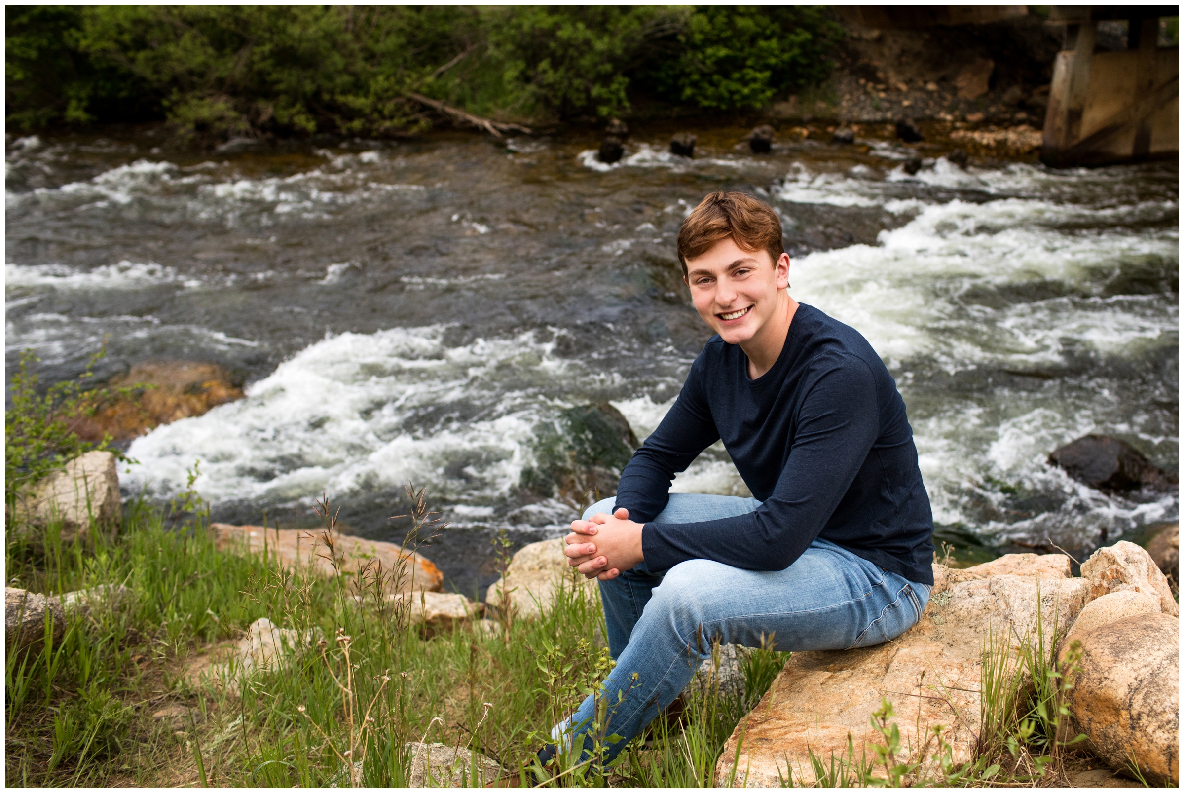 teen boy sitting next to river during Boulder CO senior portraits 