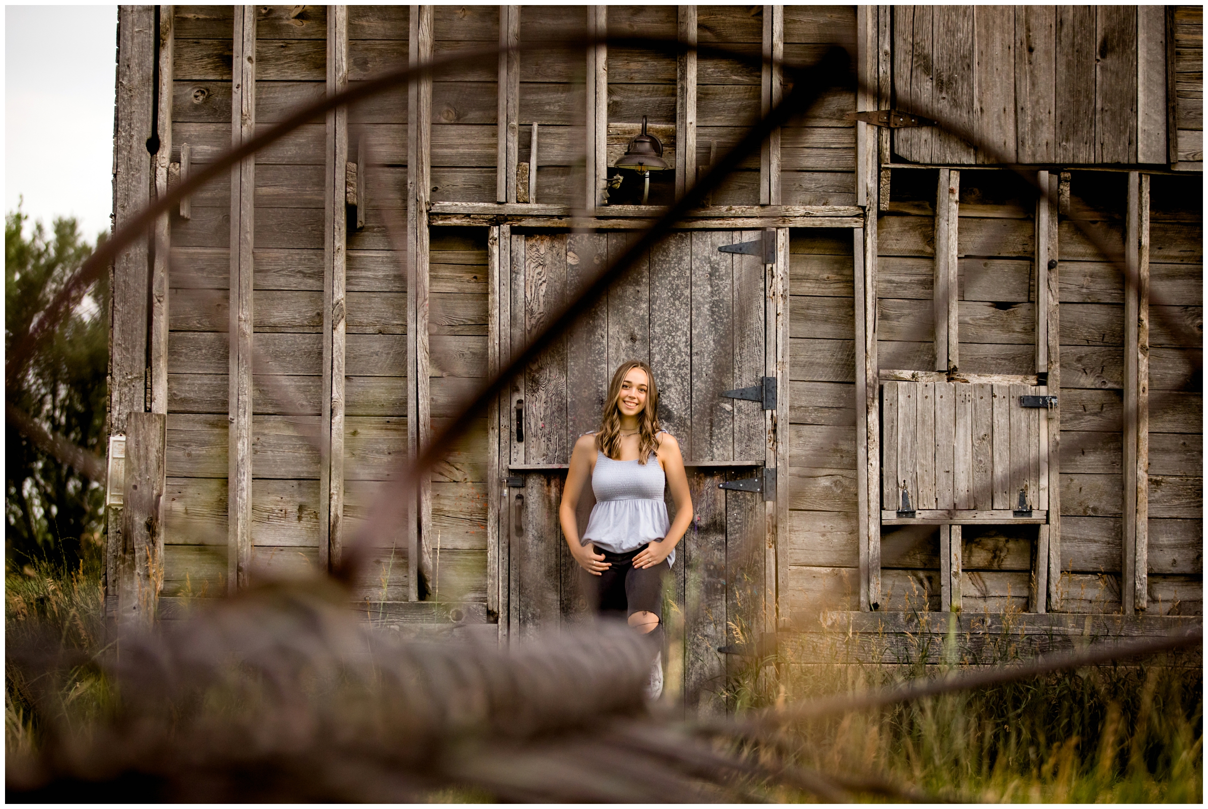 teen leaning against barn during Longmont Colorado rustic senior photos