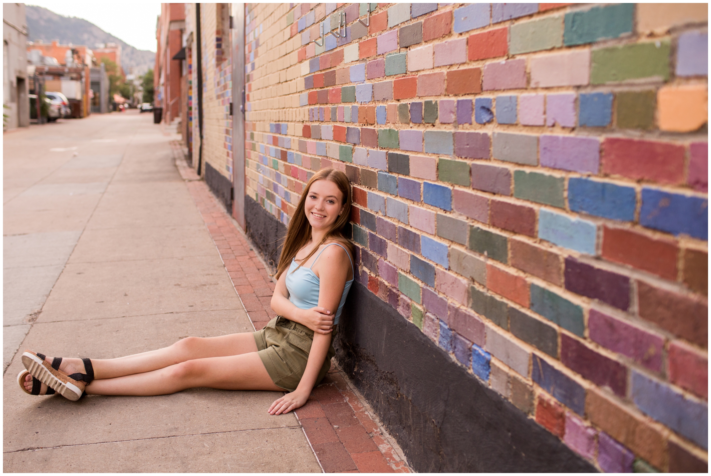 teen leaning against colorful brick wall during urban and dance senior portraits in Boulder Colorado 