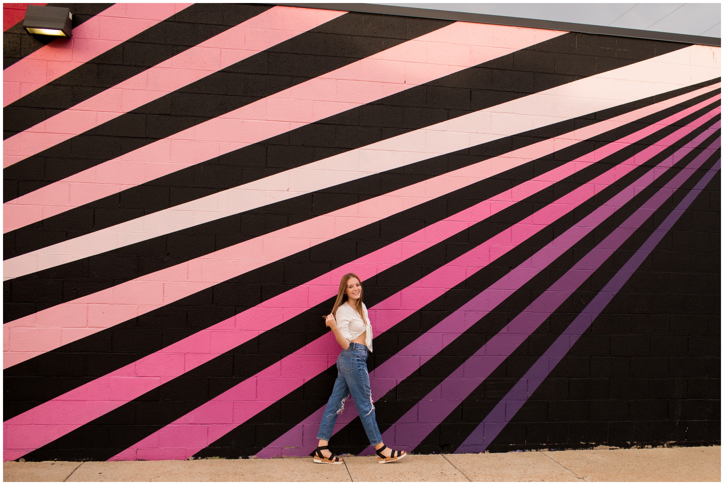 teen girl walking in front of colorful wall mural during Colorado urban senior pictures