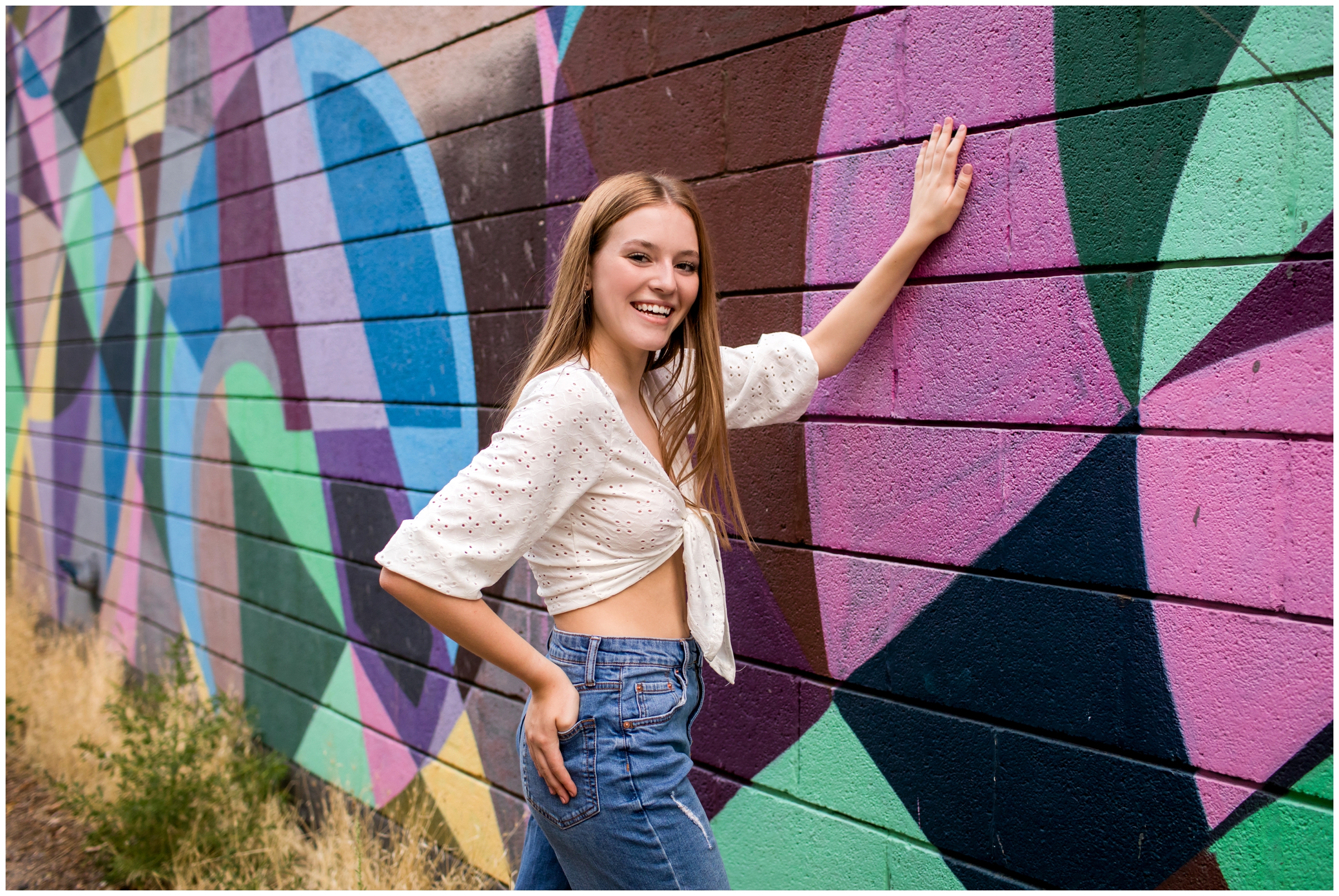 teen girl leaning against colorful wall mural during urban Boulder senior photos