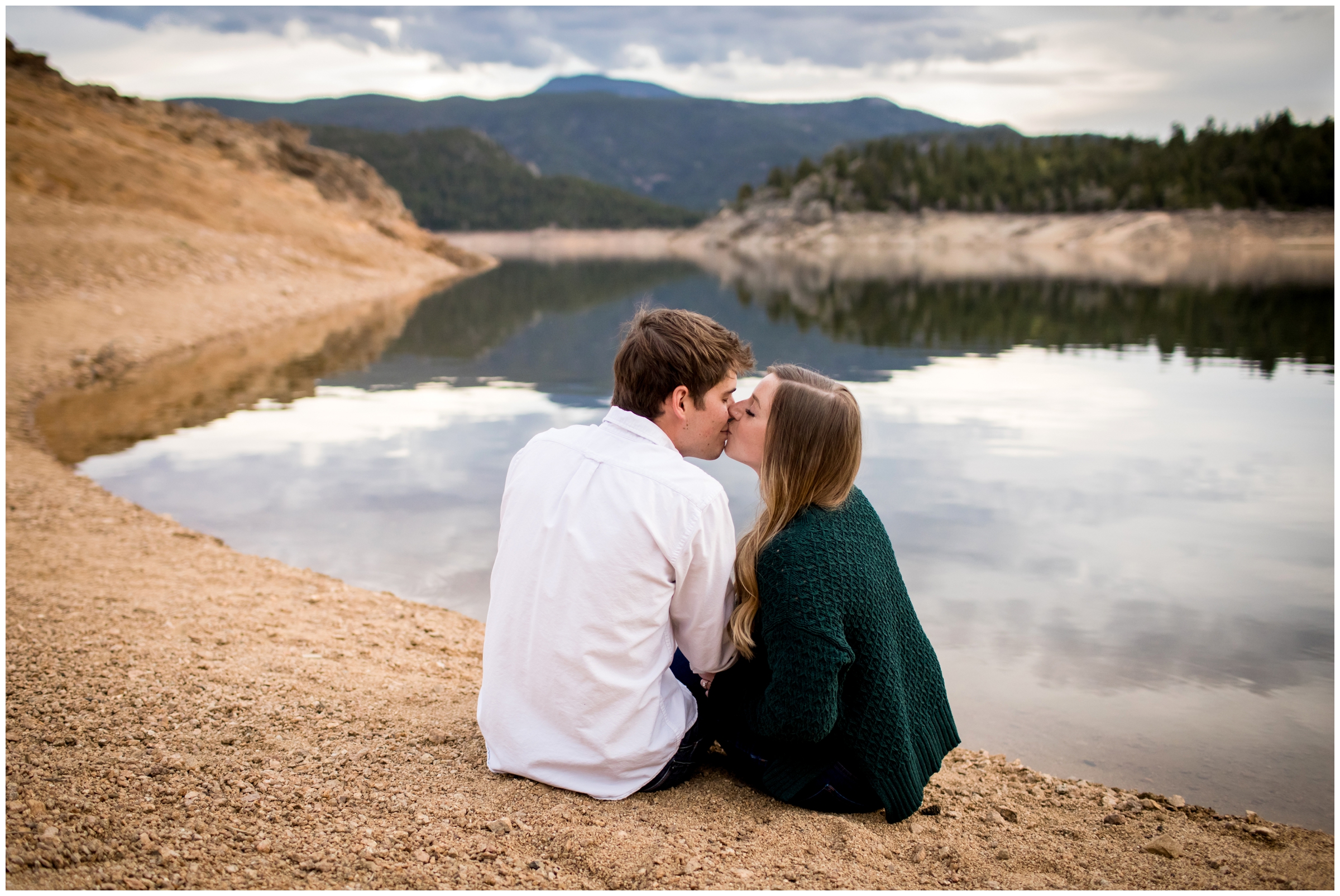 couple kissing next to mountain lake during Colorado engagement photos