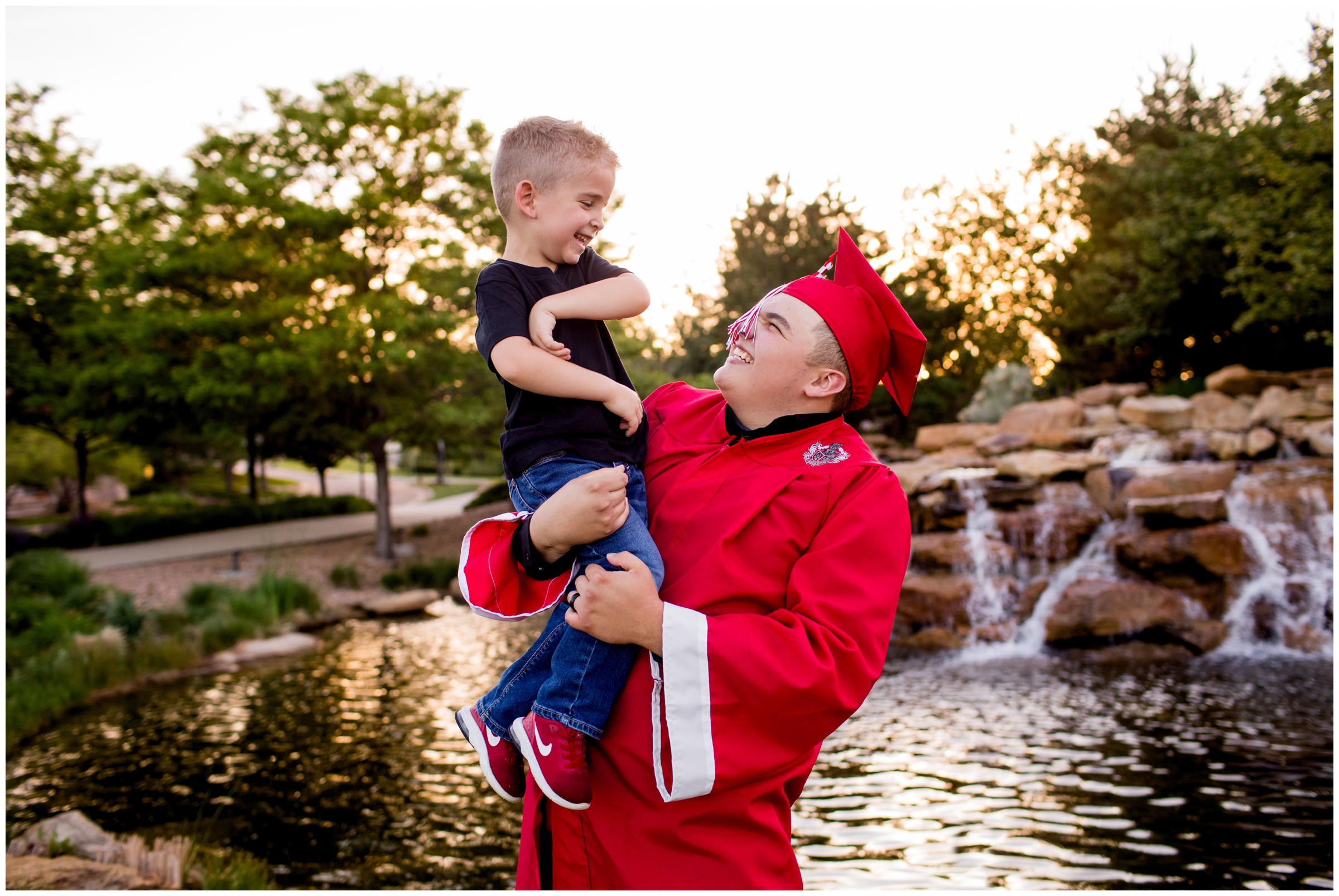 senior guy holding little brother during Colorado graduation cap and gown photo shoot by Plum Pretty Photography 