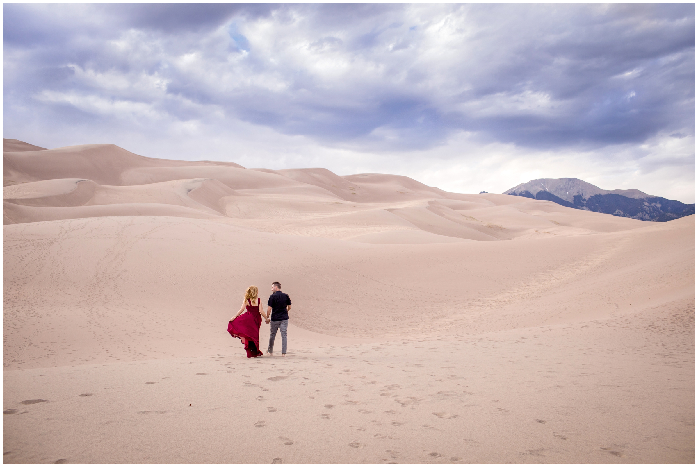 couple walking on sand dunes during Colorado adventure engagement couples photography session 