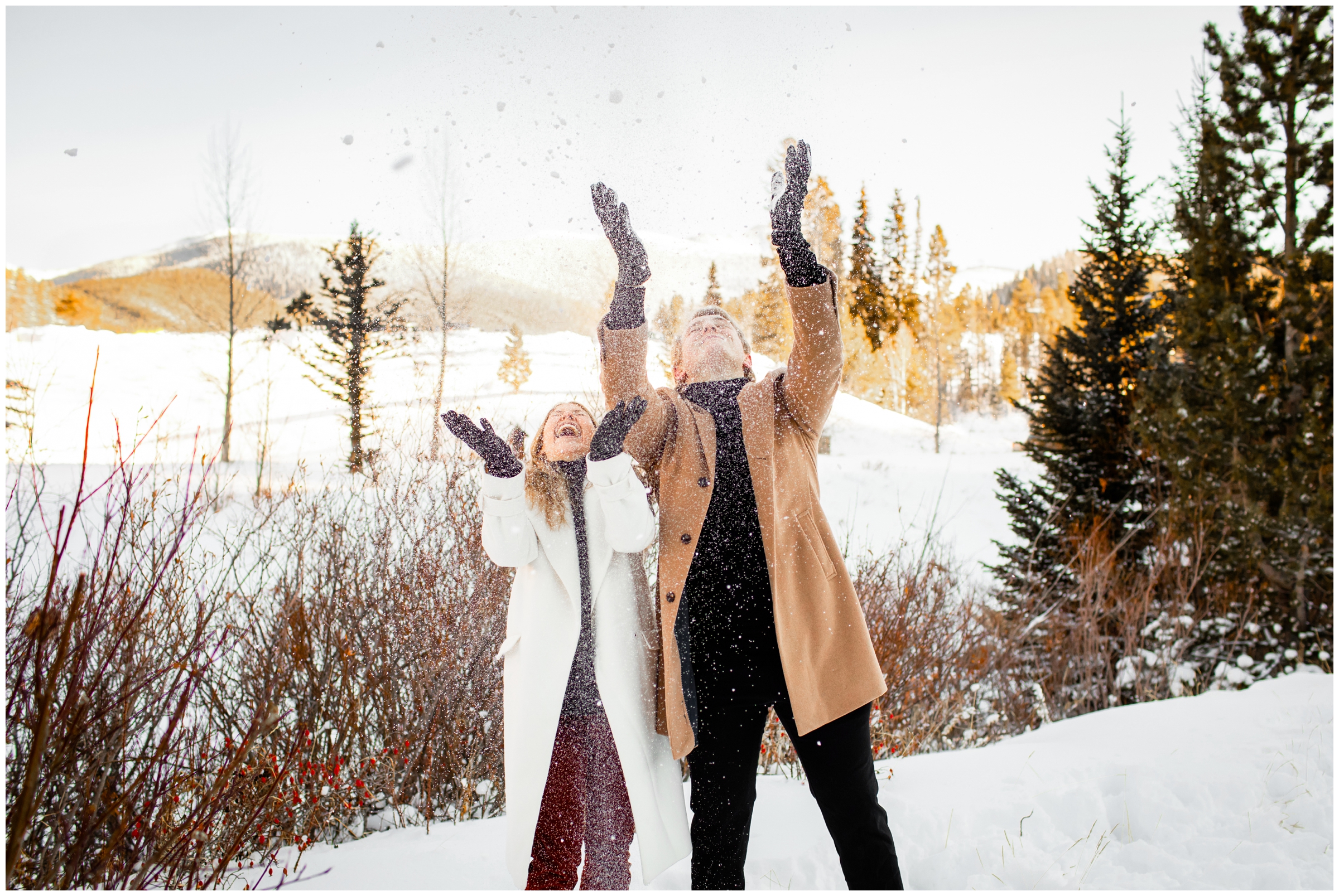 couple throwing snow in the air during Colorado winter engagement portraits at winter park resort 