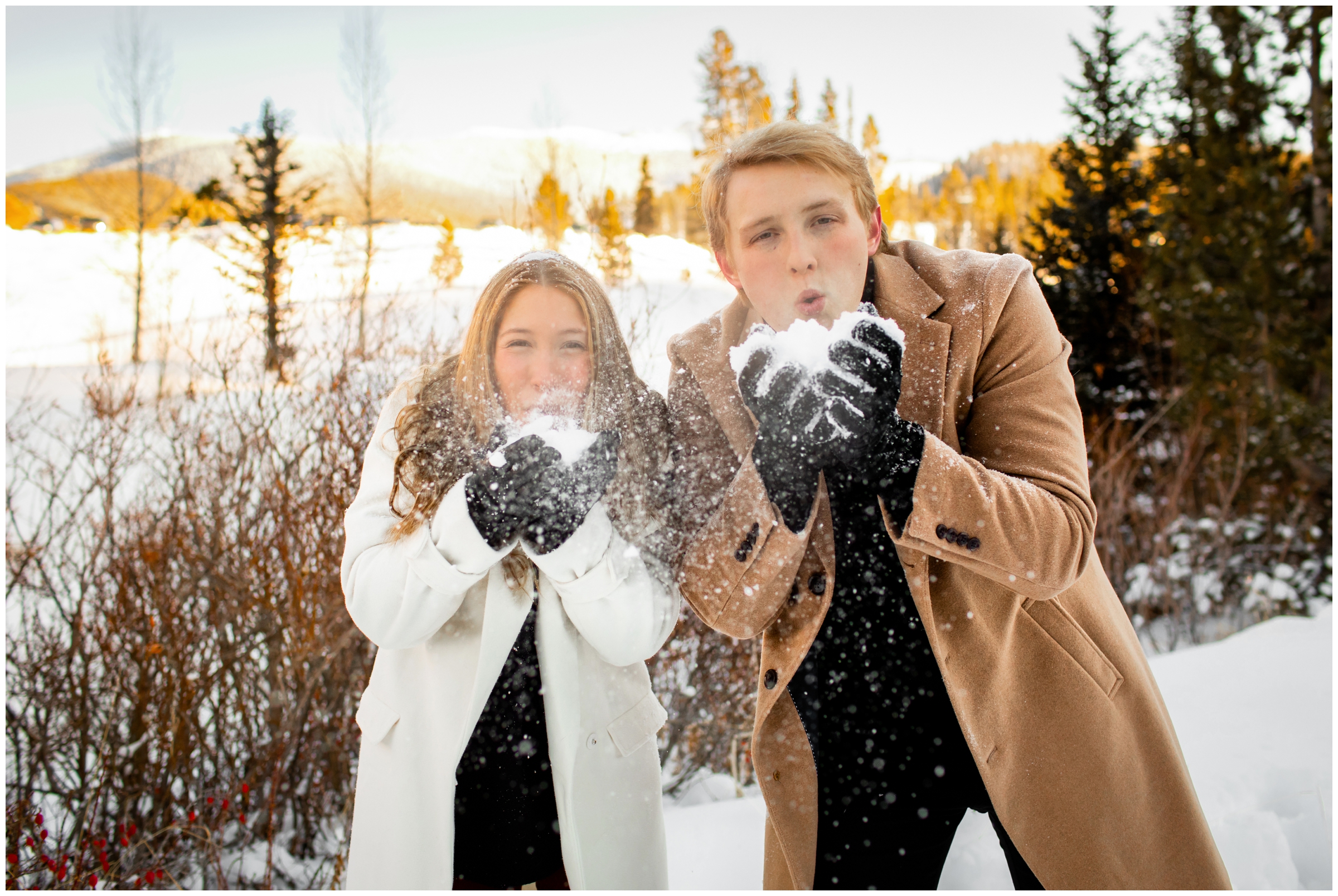 couple blowing snow at the camera during Winter Park engagement portraits 