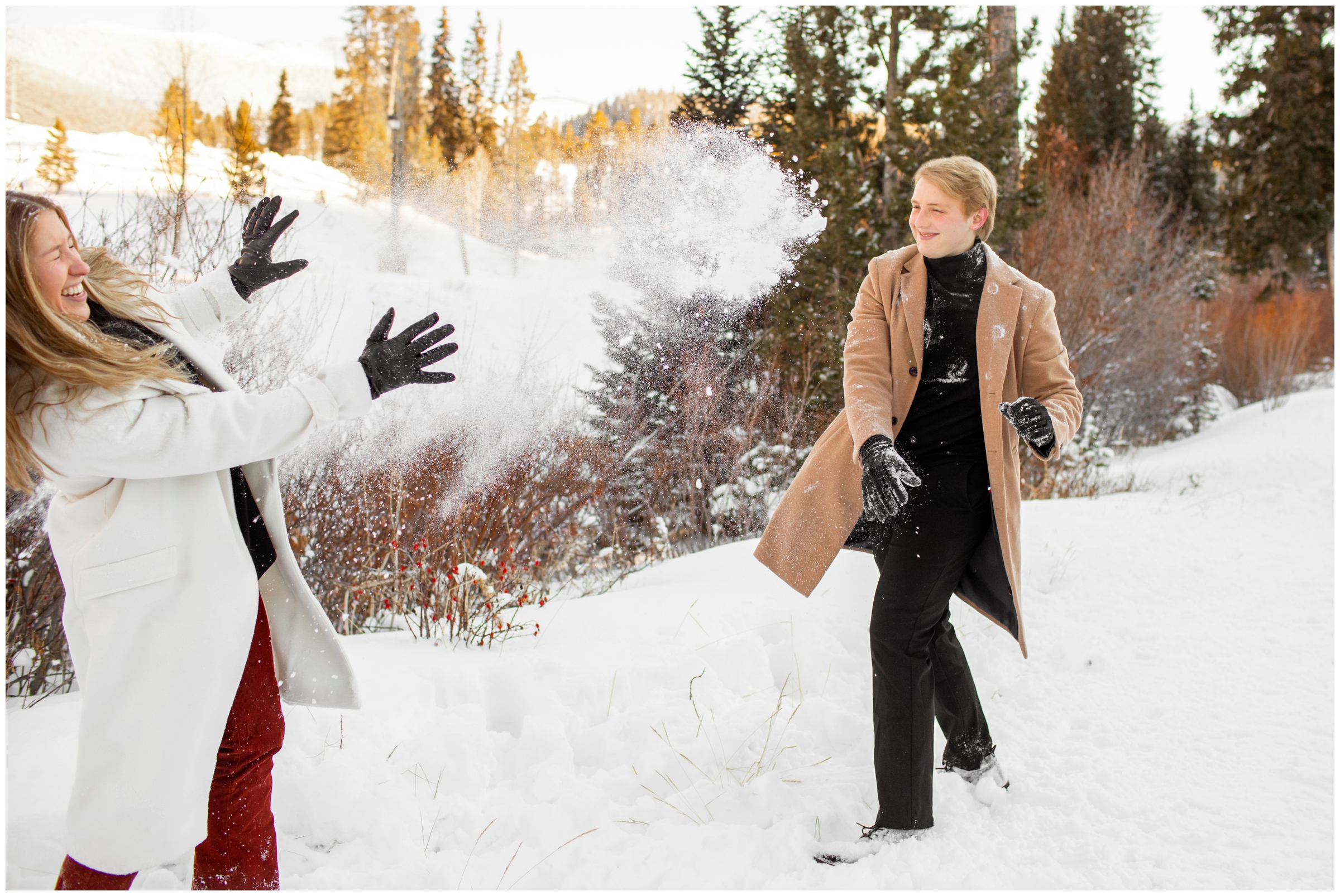 couple having snow ball fight during Colorado winter engagement photography session 