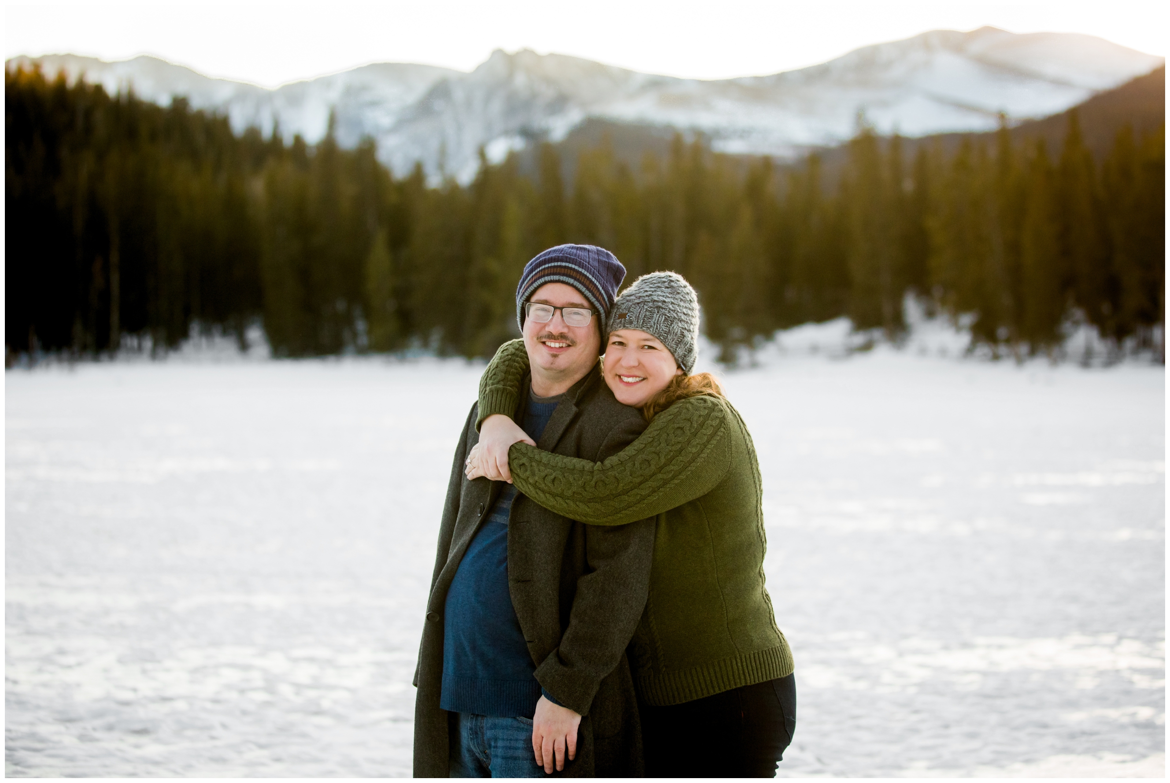 couple posing on frozen lake with mountains in background during Echo Lake Idaho Springs engagement photos 
