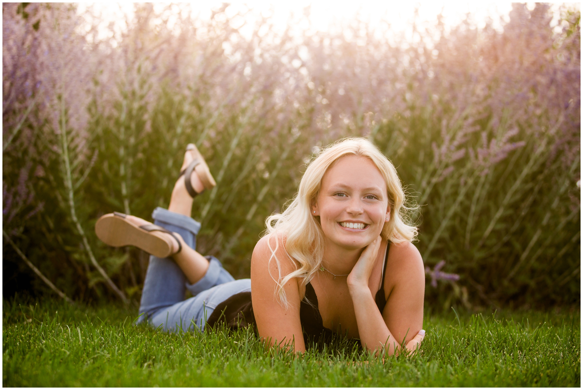 teen girl laying in grass during flower senior photography session 