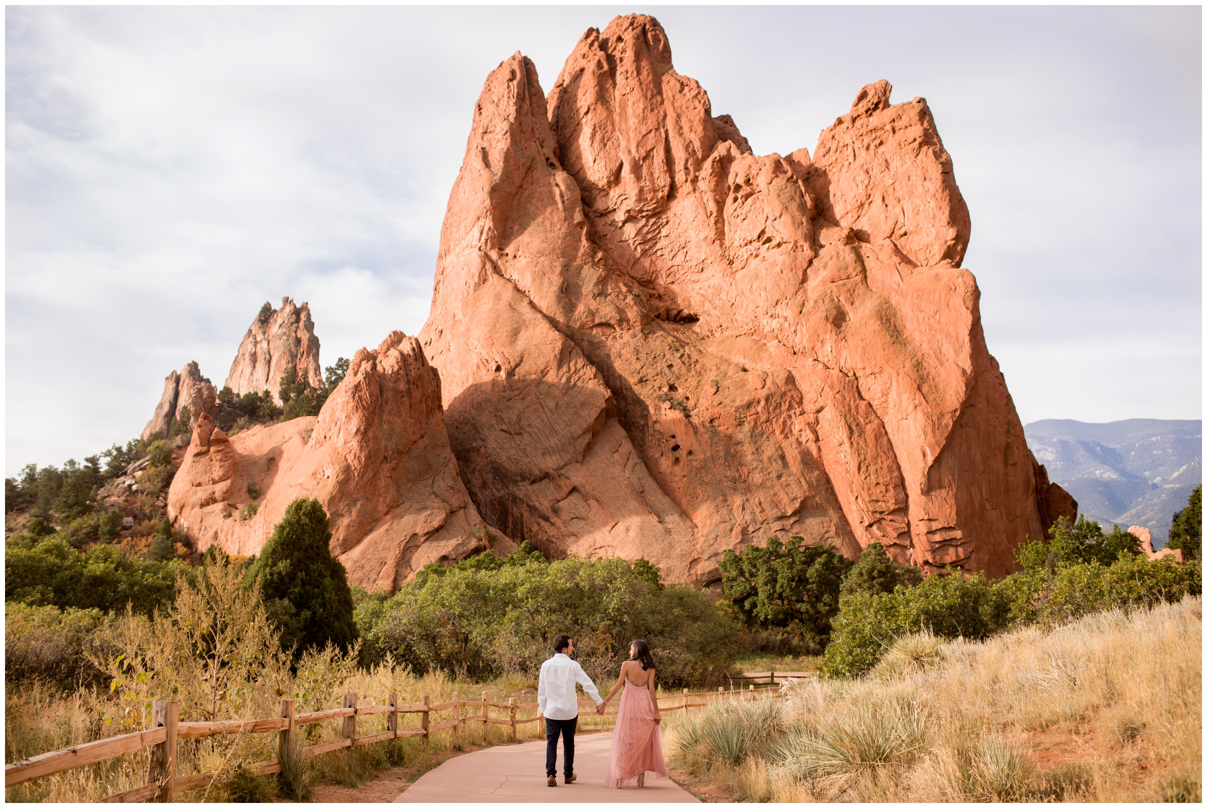 couple walking with large red rock formations during Garden of the Gods engagement photography session 