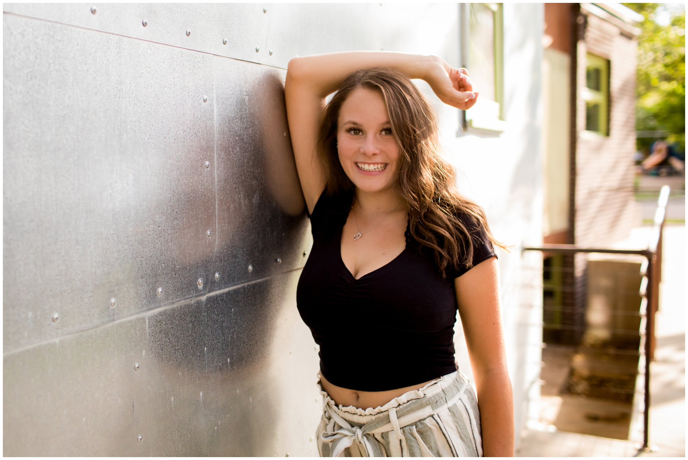 Mead High School senior leaning against metal wall during Colorado senior portrait session 