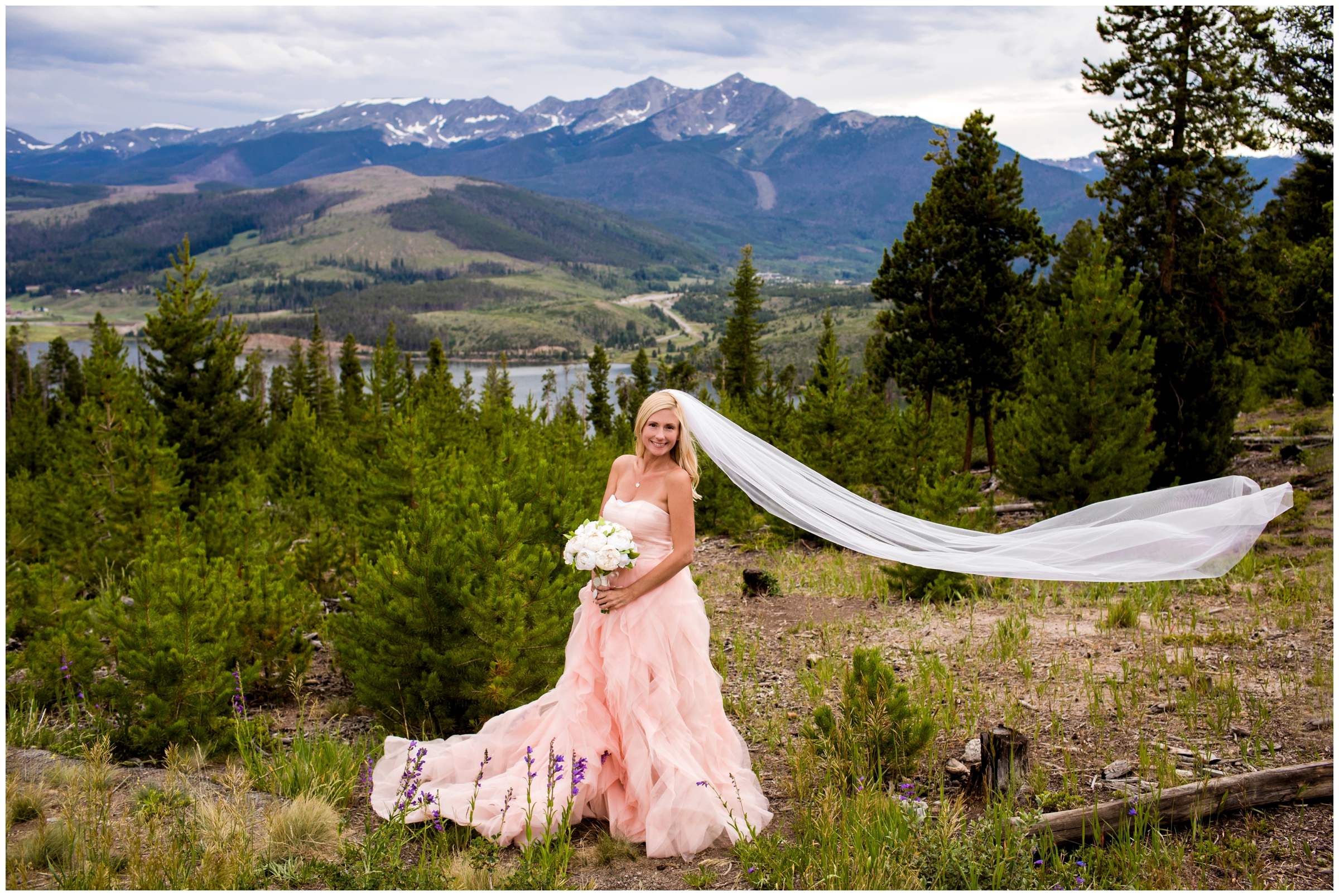 bride in pink gown posing with mountains in background at Sapphire Point 