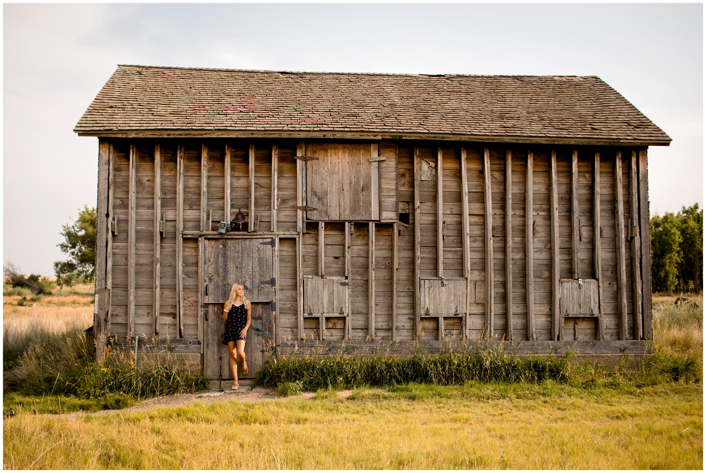 teen posing in front of barn during rustic Colorado senior pictures 