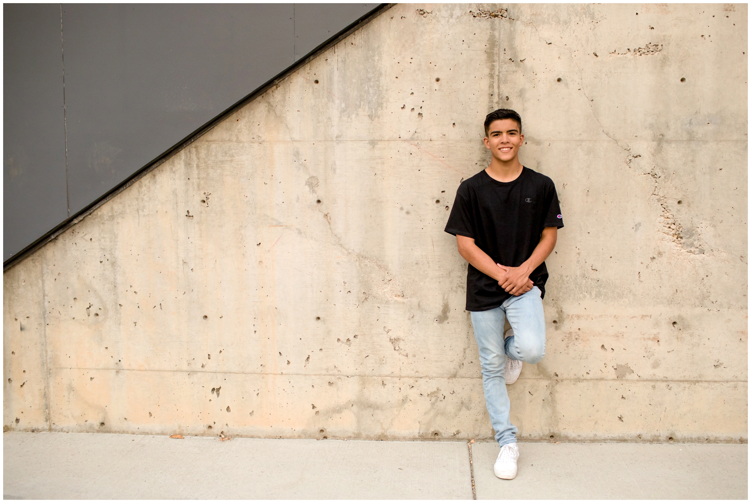 teen boy leaning against concrete wall during Colorado urban senior photography session 