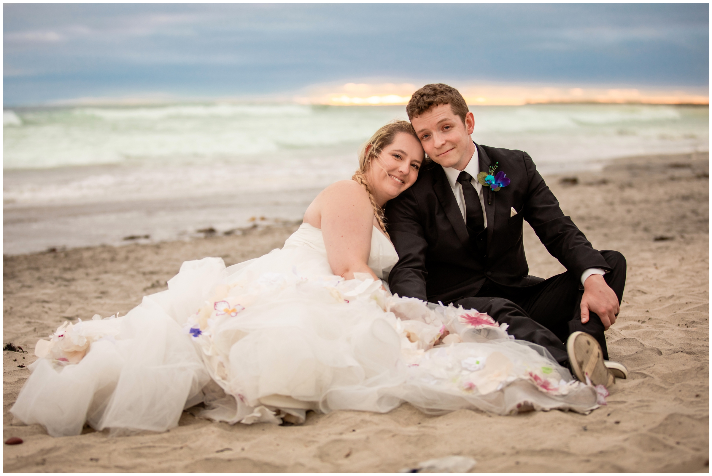 couple cuddling in the sand during Carlsbad California beach wedding newlywed photos