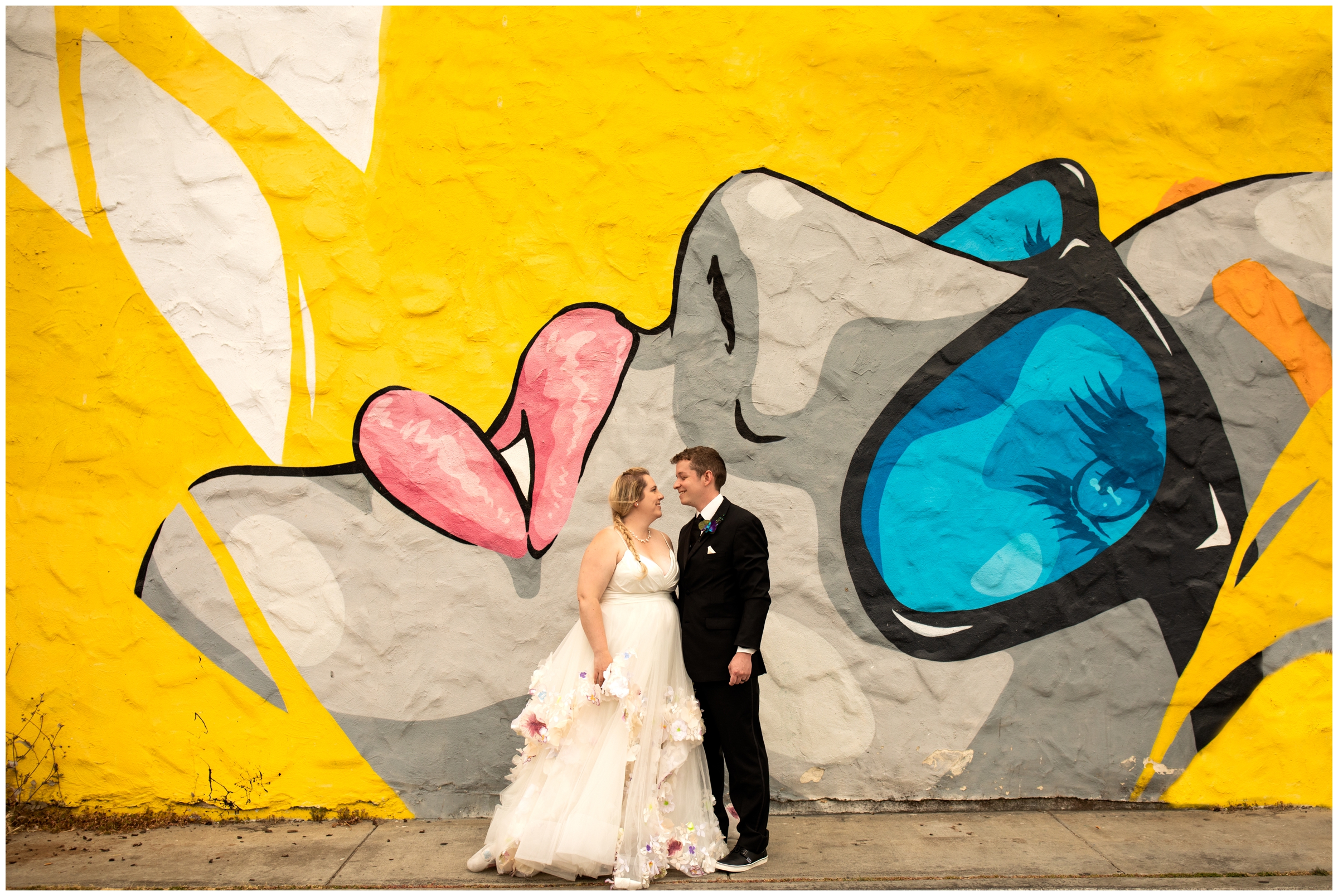 couple posing in front of wall mural during urban city wedding portraits in Denver Colorado 