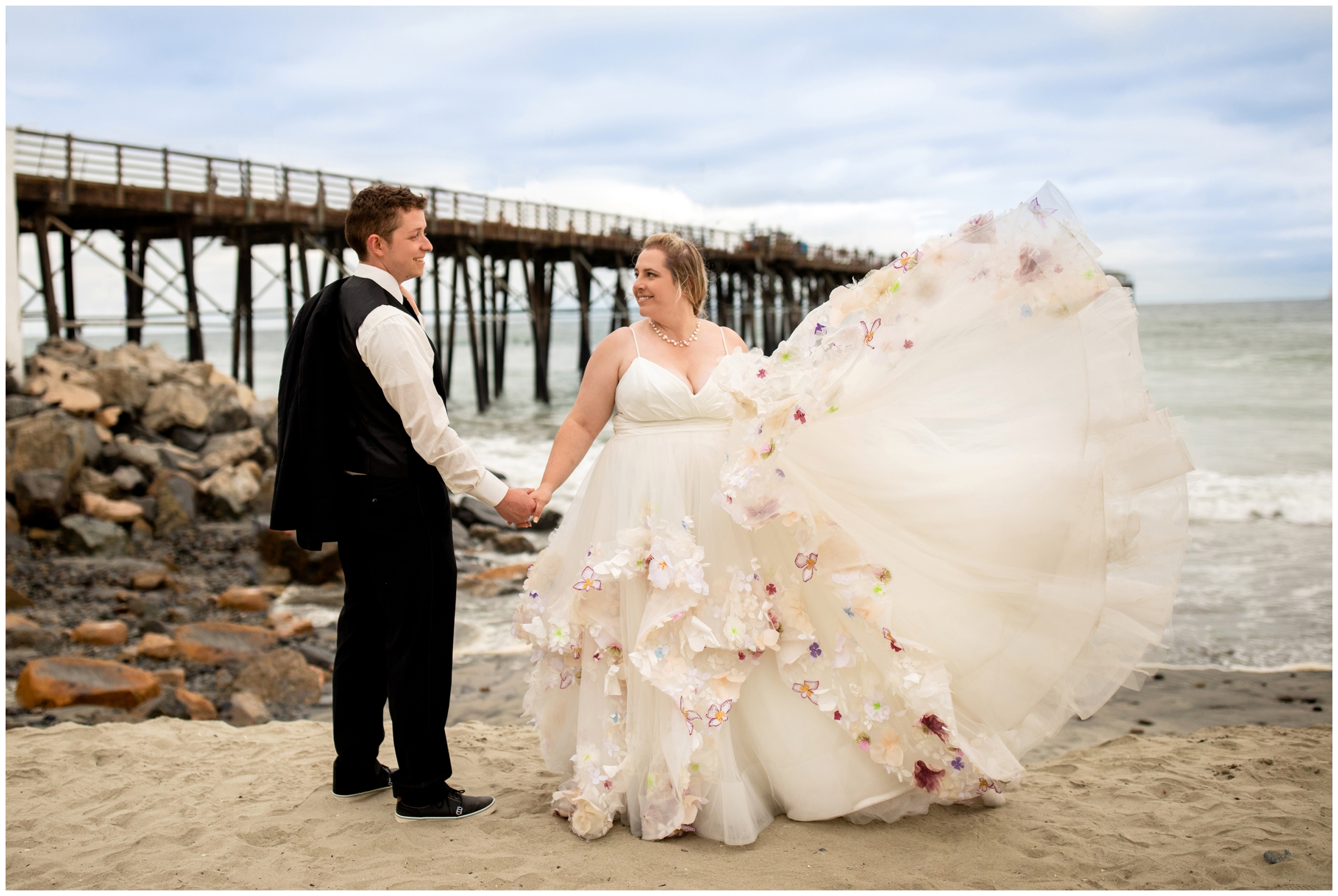bride in colorful Hayley Paige wedding dress posing for wedding portraits at Oceanside Pier in Carlsbad California 