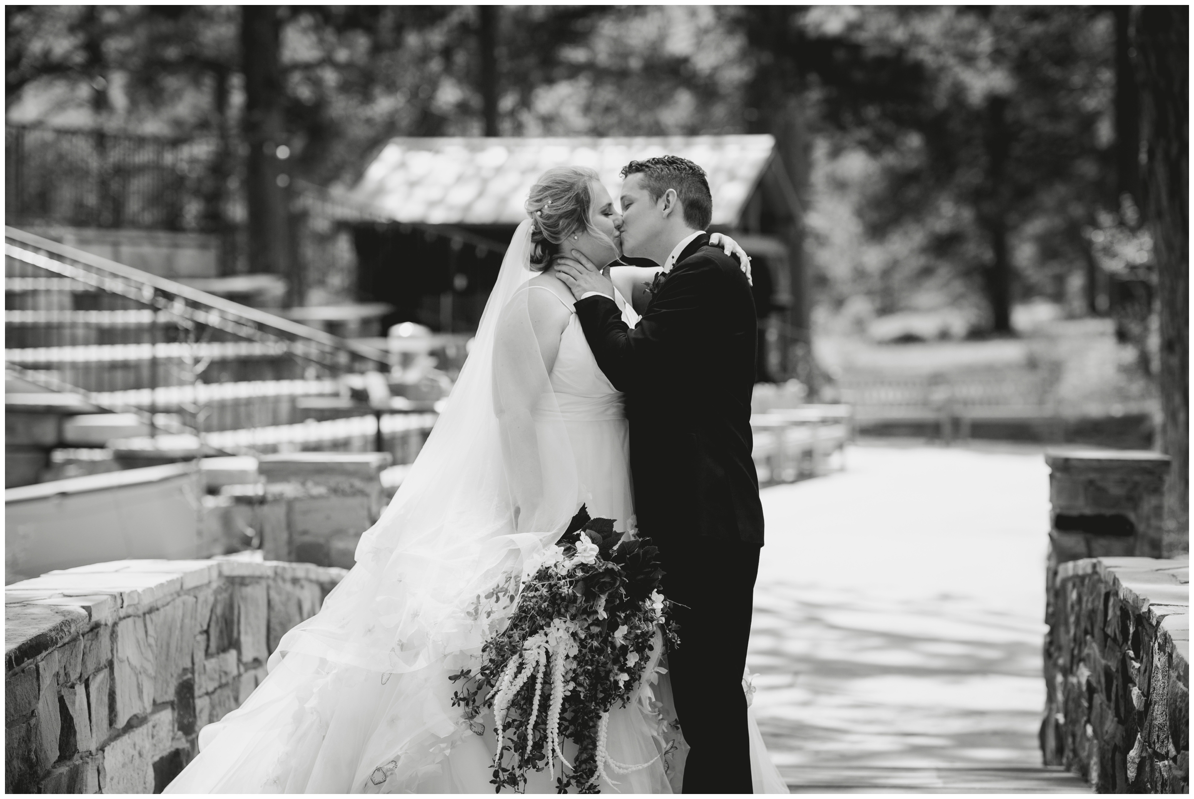 couple kissing on bridge during Estes Park spring wedding photos at Della Terra 