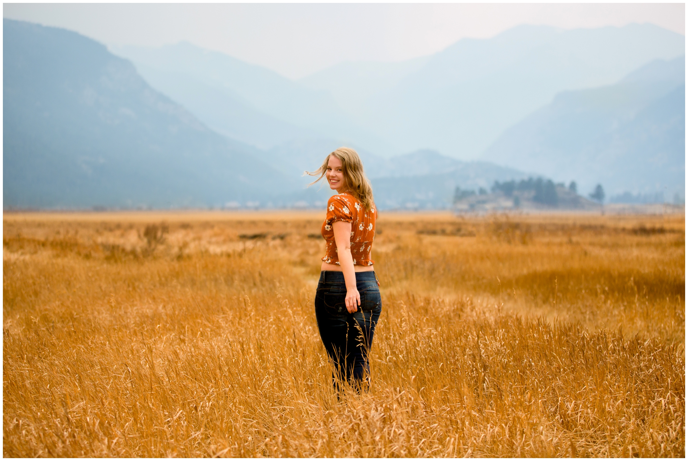 teen walking through field of long grasses during RMNP Estes Park senior pictures 