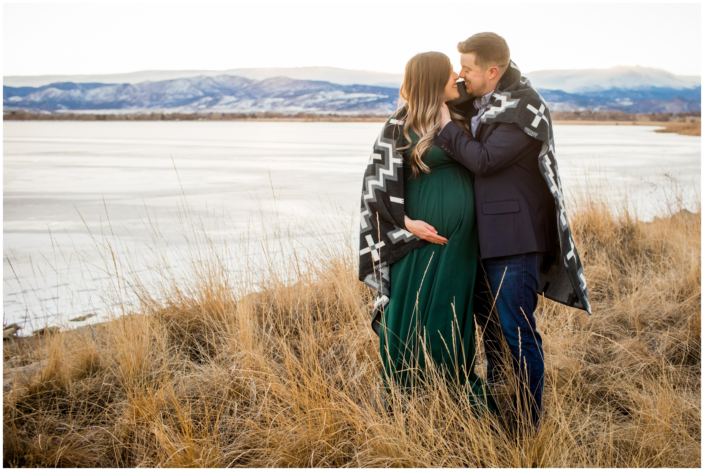 couple snuggling in blanket during Longmont Colorado winter maternity photos at McIntosh Lake