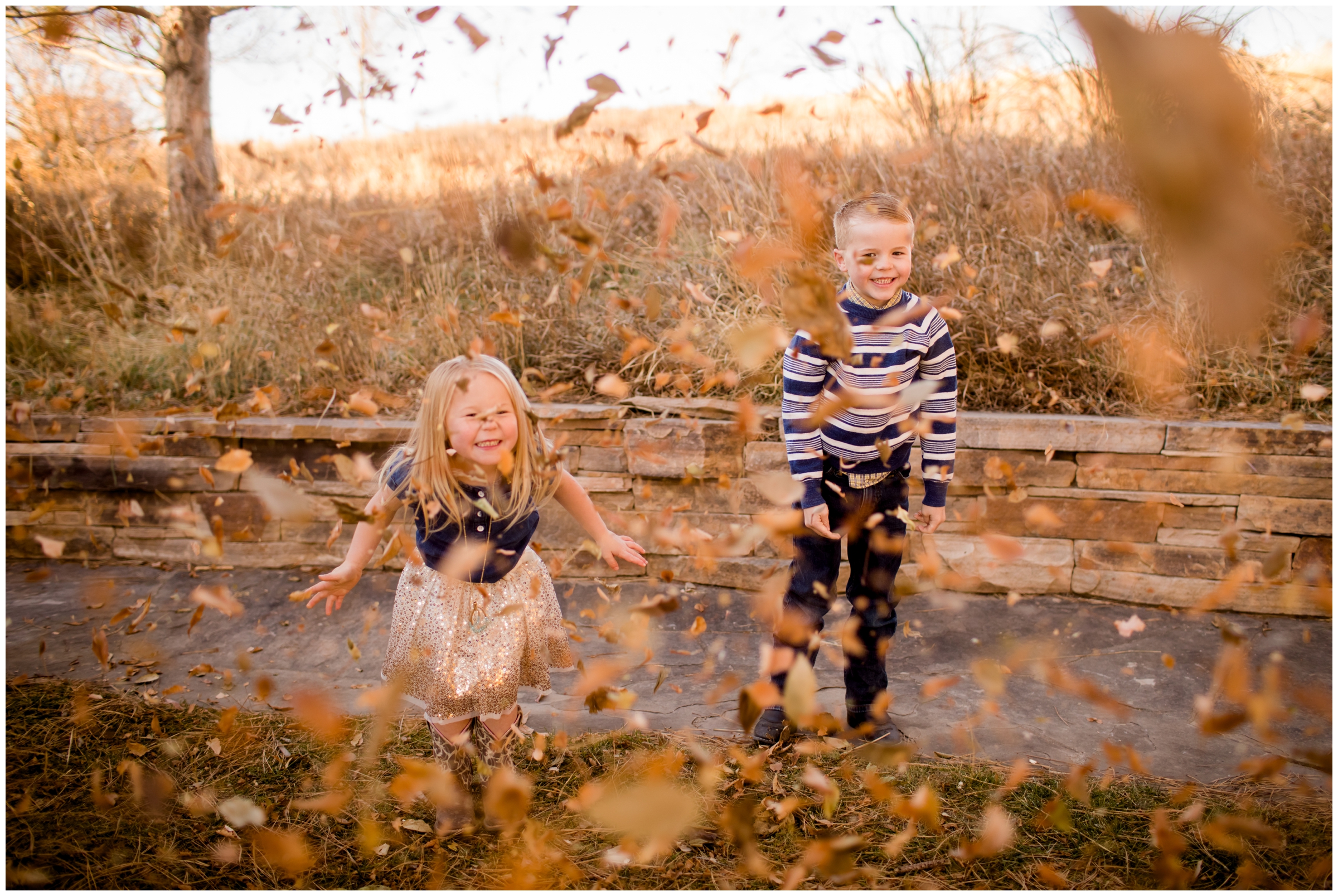 kids throwing leaves at the camera during Colorado fall family pictures 