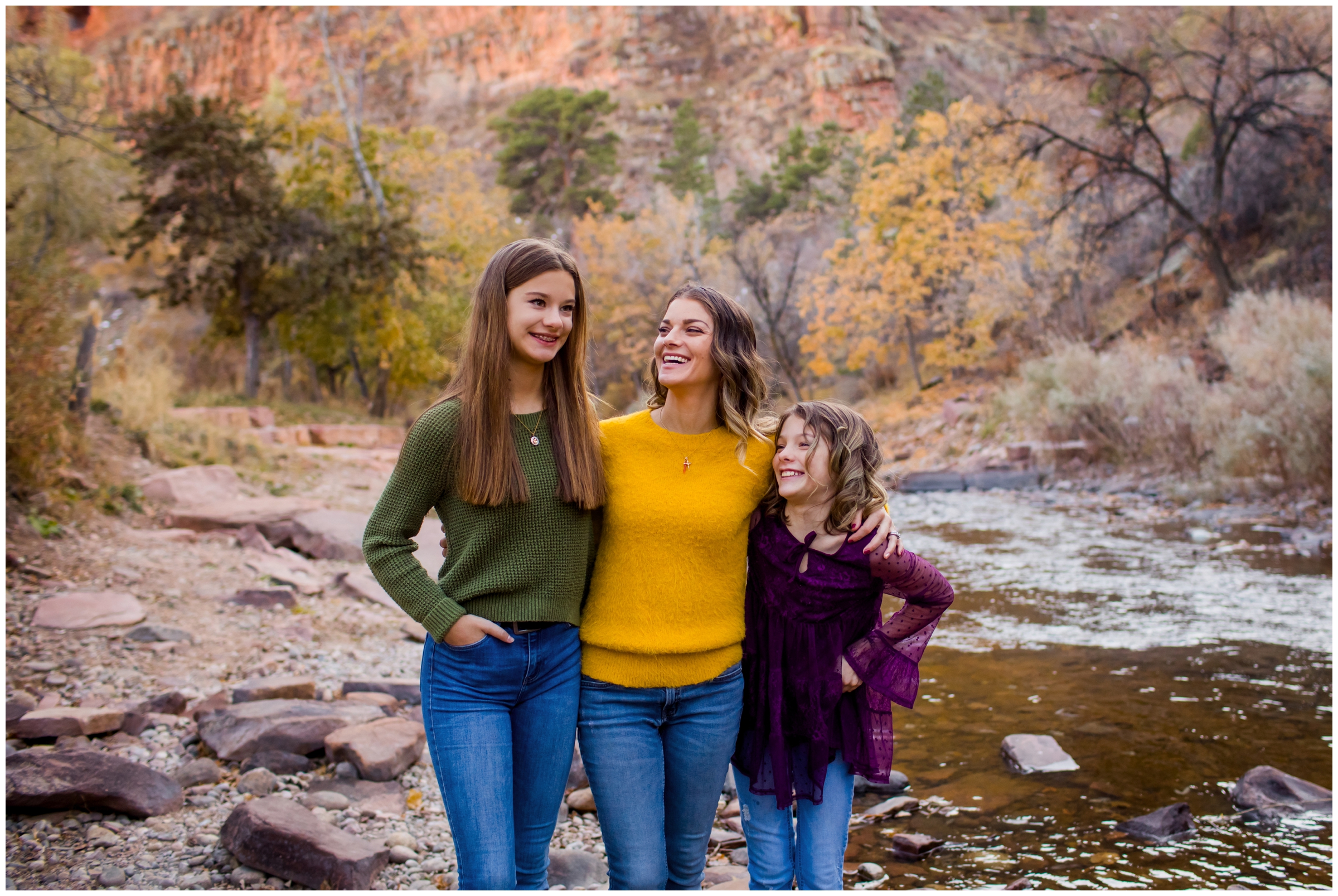 mom laughing with daughters during Lyons Colorado fall family portraits next to the river
