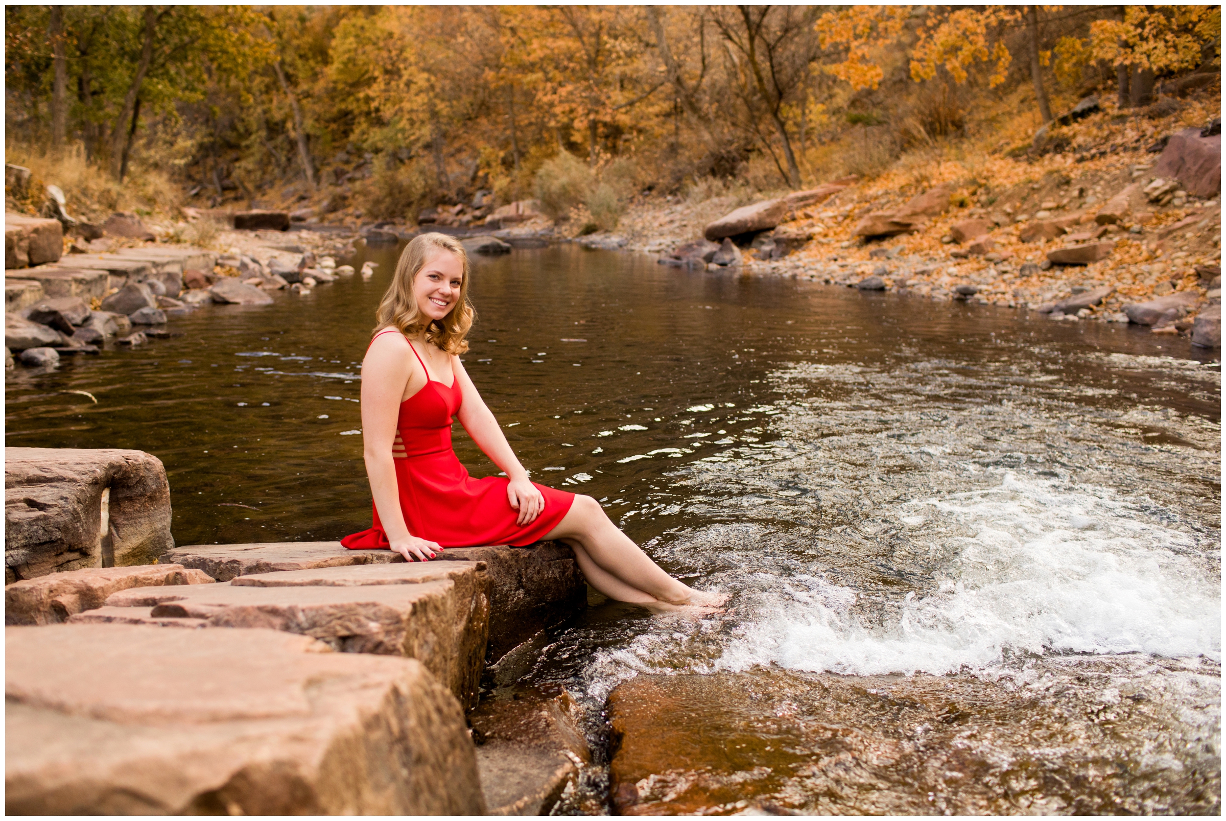 teen sitting with water in a mountain river during Colorado senior photography session 
