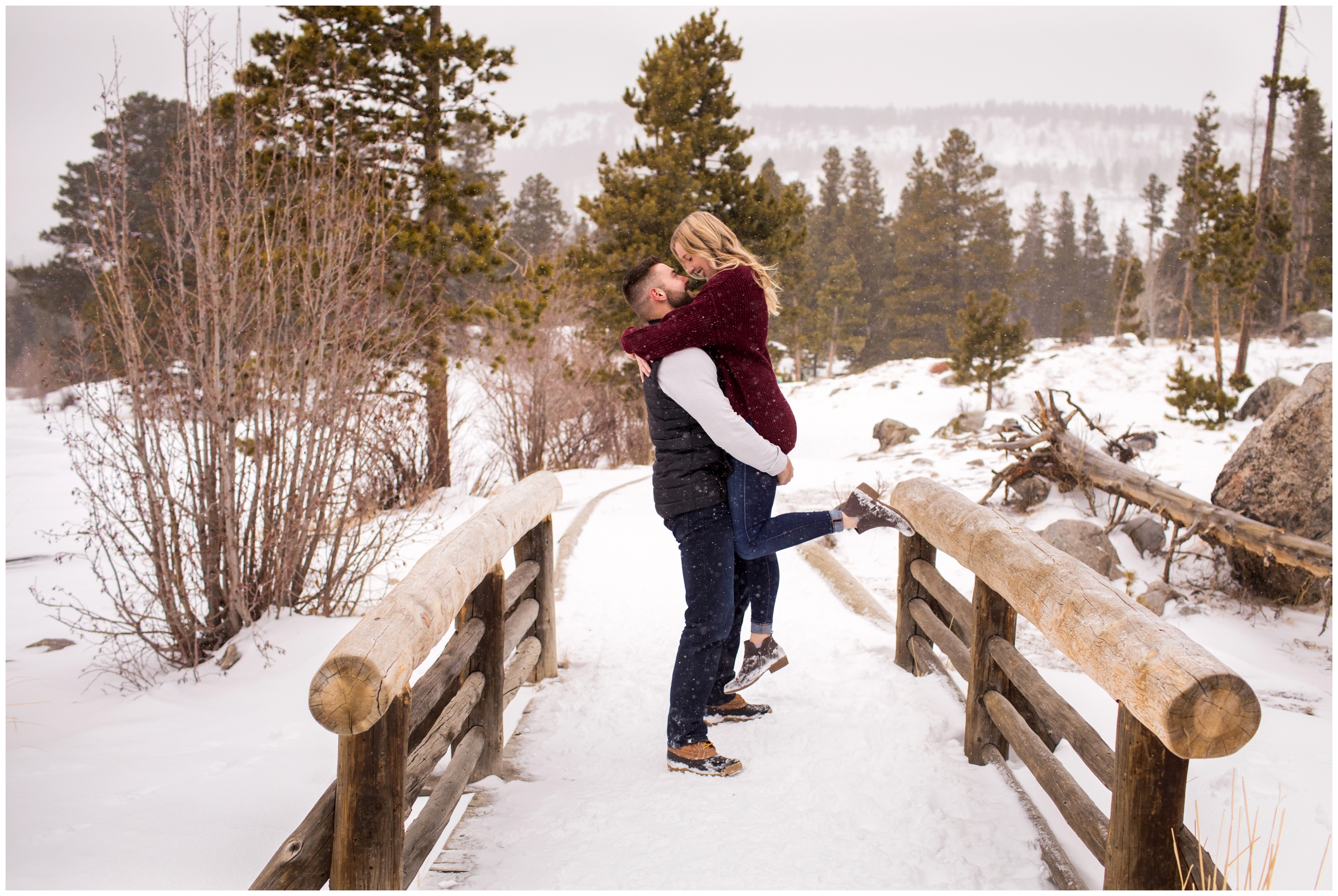 Guy lifting fiancé on a bridge during RMNP winter engagement photos 