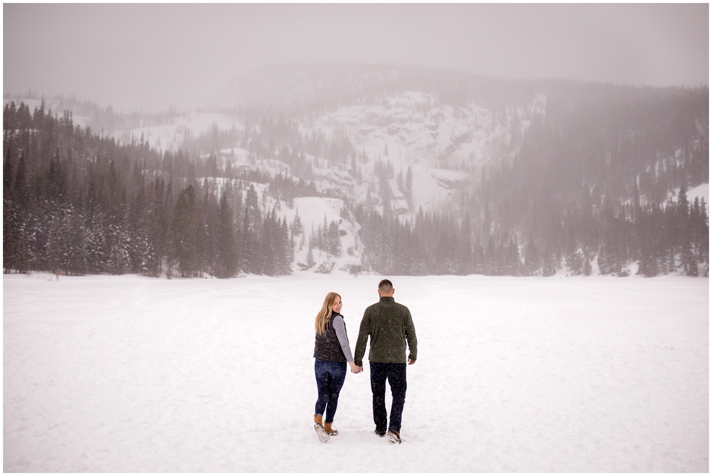 couple walking on frozen lake during Estes park winter engagement photos 