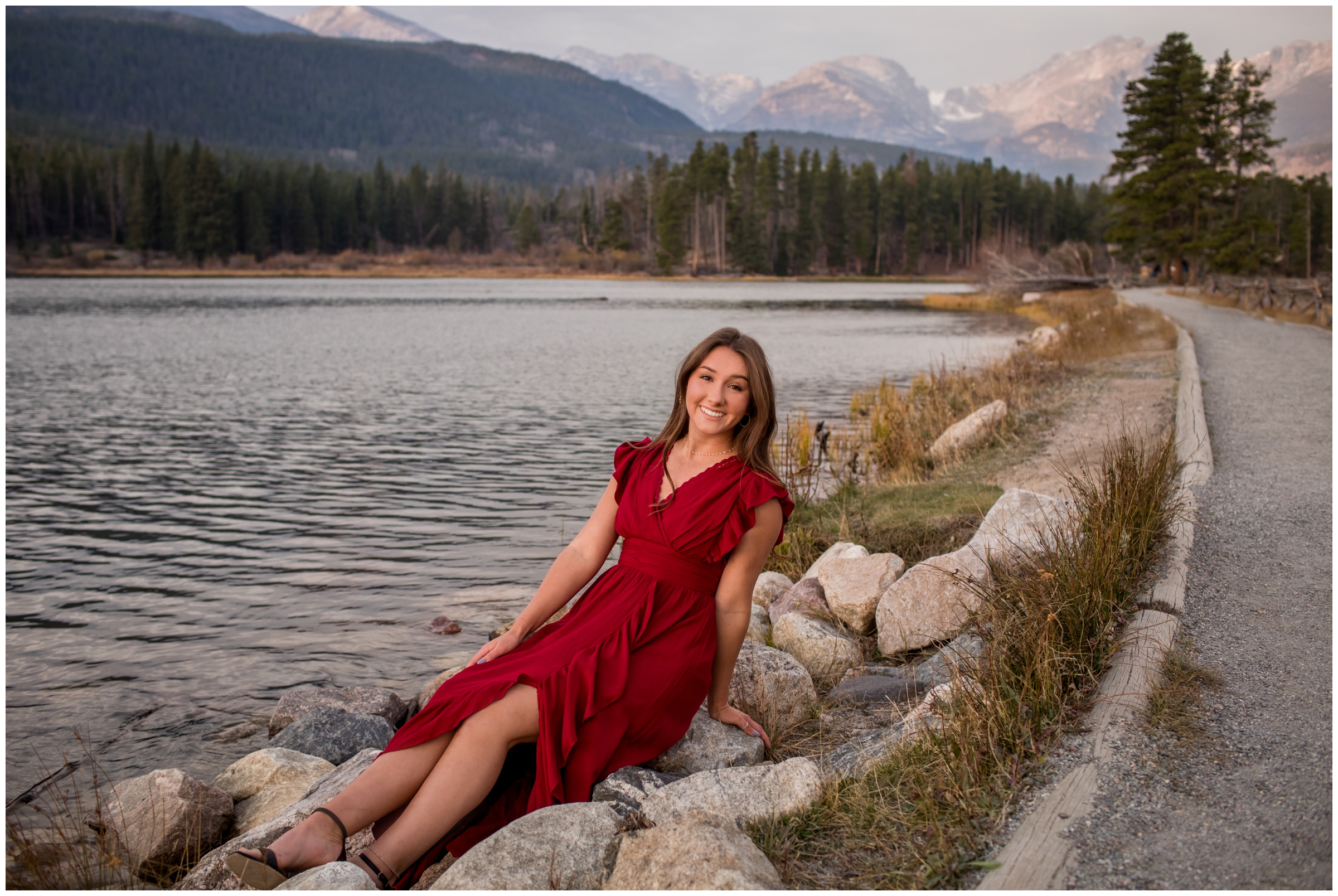 teen girl sitting on rocks with Sprague Lake in background during Estes Park graduation portraits 