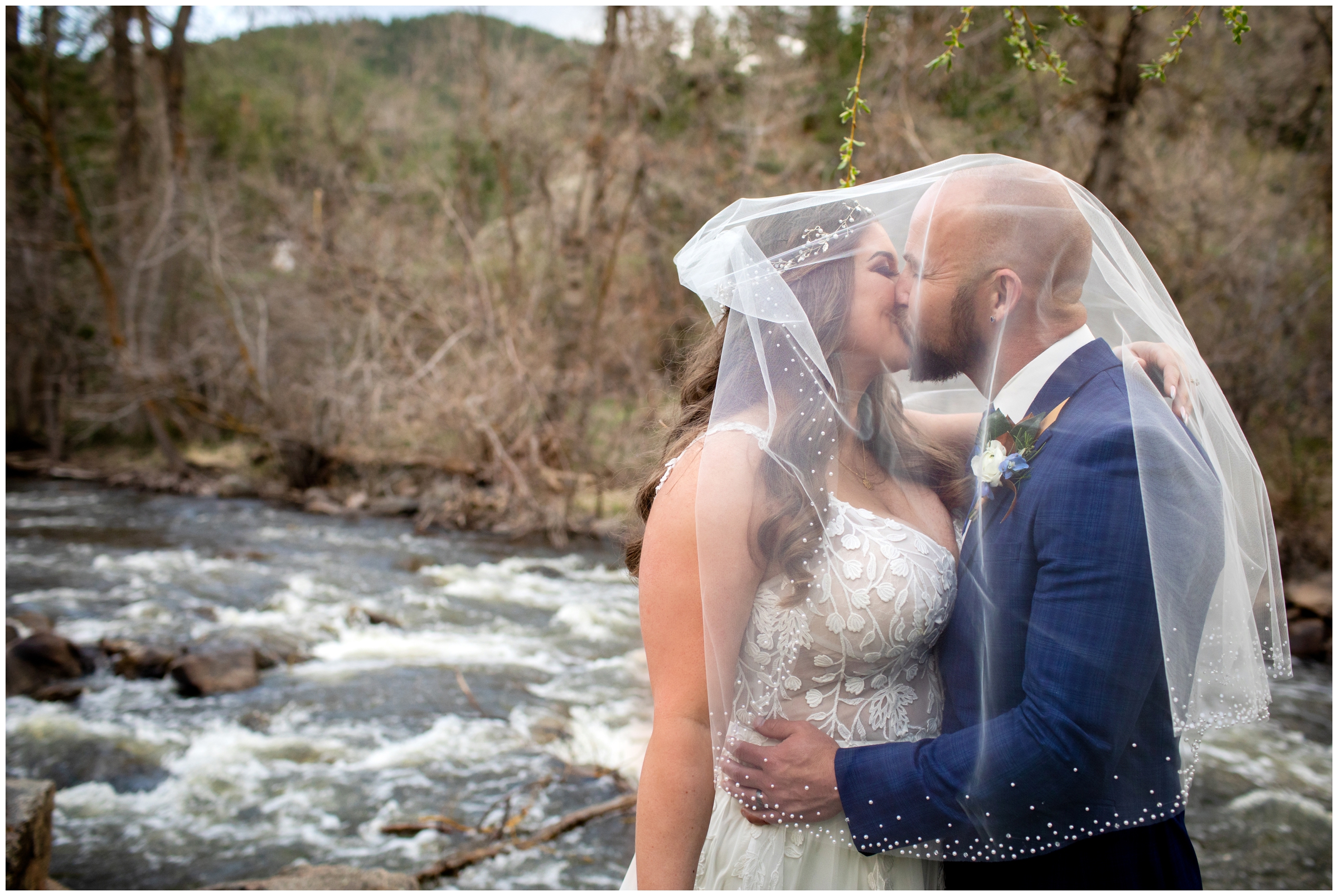couple kissing under bride's veil during Boulder wedding pictures by the river