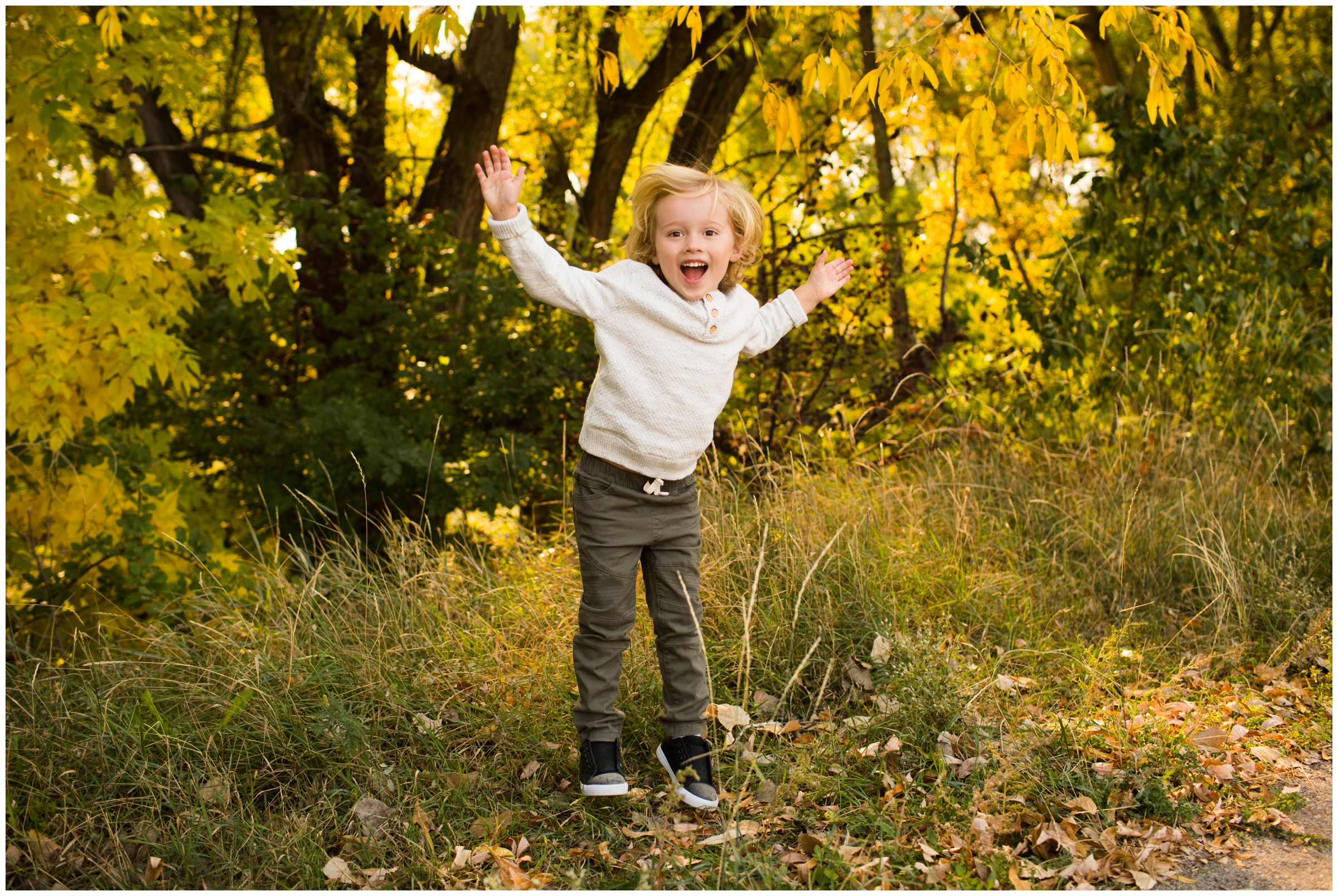 little boy jumping with fall foliage in background during Longmont Colorado family photography session 